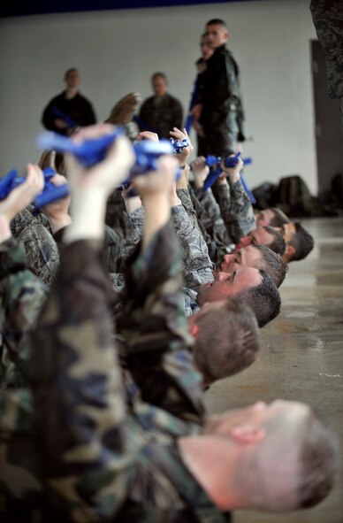 MOODY AIR FORCE BASE, Ga. -- A group of air liaison officer assessment participants hold their guns in the air as they perform leg lifts over the edge of the pool March 23. The participants had an hour of physical training after their two hours of water confidence training. (U.S. Air Force photo/Airman 1st Class Nicholas Benroth)(RELEASED)
