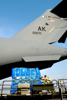 Staff Sgt. Jason Doyle and Senior Airman Joshua Buckner, both air transportation Airmen, move supplies onto a C-17 Globemaster III on March 20, 2011, at Yokota Air Base, Japan. The supplies were transported to Sendai Airport to be used for humanitarian assistance bringing relief to Japan after the earthquake and tsunami disaster. Doyle and Buckner are assigned to the 730th Air Mobility Squadron. (U.S. Air Force Photo/Staff Sgt. Jonathan Steffen) 