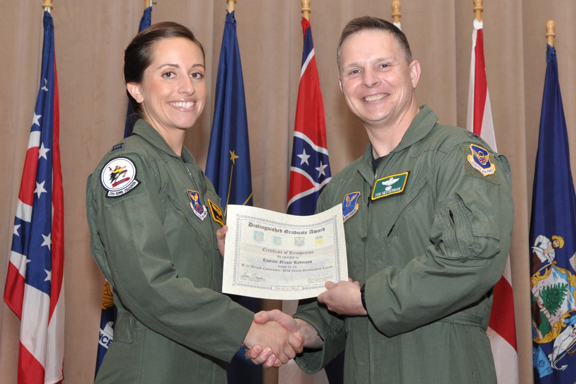 Capt. Nicole Redmond, a Pilot Distinguished Graduate for Formal Training Unit Class 10-03, poses for a photo with Col. Thomas P. Hesterman, the 2nd Bomb Wing vice commander, during graduation ceremonies in Hoban Hall at Barksdale Air Force Base, La., March 11, 2011. The Distinguished Graduate Award is a culmination of academics tests, flight evaluation, officership, attitude and professional bearing. Students selected for the award have demonstrated a level of performance that is clearly above their peers.  There is usually only one awarded for each specialty. Class 10-03 had a tie between two students for Aircraft Commander (Pilot) DG. Captain Redmond tied for the award with Capt. Russel Kirklin. Graduates of the 93rd Bomb Squadron's Formal Training Unit covered several aspects of B-52H Stratofortress operations during their training, which lasted approximately two years. The FTU is in charge of training Airmen to fly the B-52.  To accomplish this task of forging new aviators into Combat Ready B-52 crewmembers takes the work of both AF Reserve and Active Duty Members. Twenty-four students graduated from Class 10-03 and will now report for duty to squadrons throughout the B-52 community. (U.S. Air Force photo/Tech. Sgt. Jeff Walston)