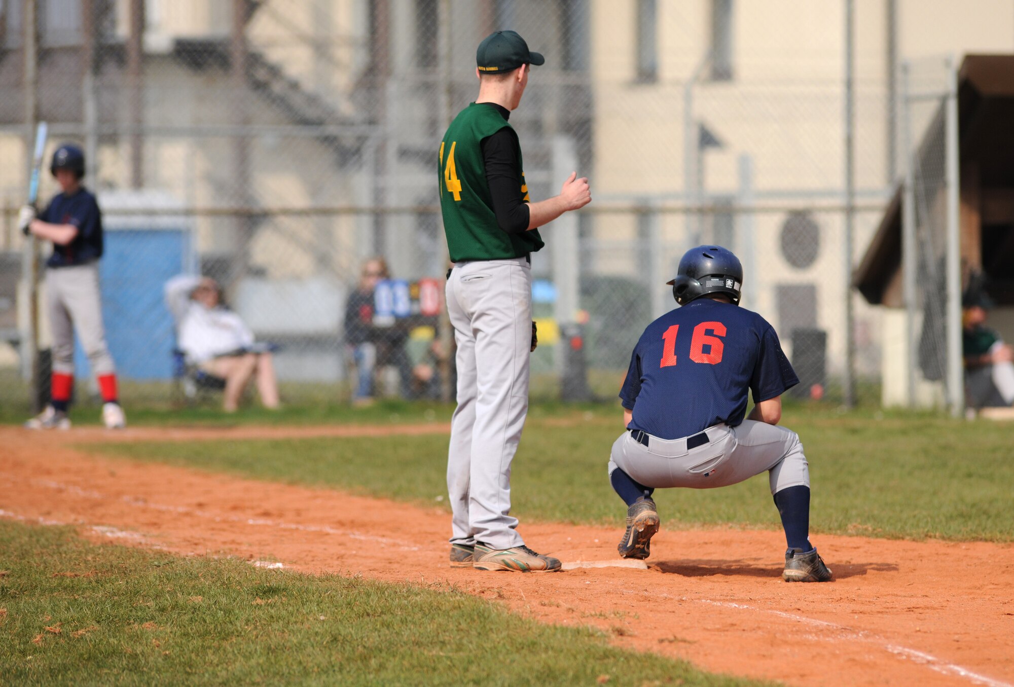 SPANGDAHLEM AIR BASE, Germany – Bitburg High School junior Zach Nichols, right, takes a moment to rest after sprinting to first base as Supreme Headquarters Allied Powers Europe American High School junior Sam Manns looks on during the opening game of the season here March 26. The SHAPE Spartans defeated the Bitburg Barons 5-4 the first game of a doubleheader. The Barons defeated the Spartans 12-3 the second game. (U.S. Air Force photo/Senior Airman Nathanael Callon)