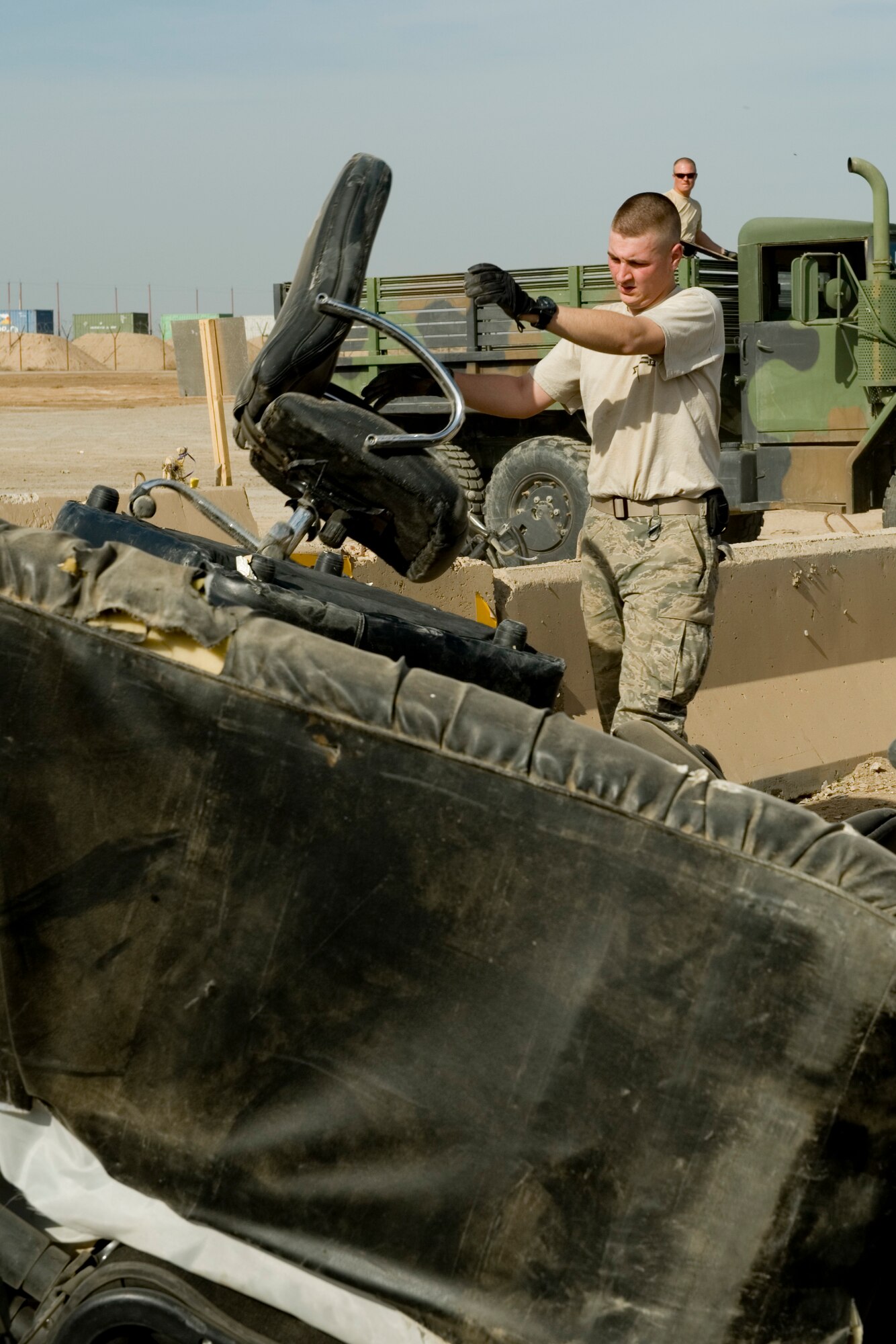SATHER AIR BASE, Iraq -- Senior Airman Justin McGhee, 447th Expeditionary Security Forces Squadron member, places unserviceable office furniture into a temporary dump site March 19. The collection point was set up in conjunction with "Operation Clean Sweep," which was an effort to reduce bulk trash on base in anticipation of relocating forces at the end of the year. Airman McGhee is deployed from the178th Security Forces Squadron, Springfield, Ohio, and is a native of Greenville, Ohio. (U.S. Air Force photo by Staff Sgt. Levi Riendeau)