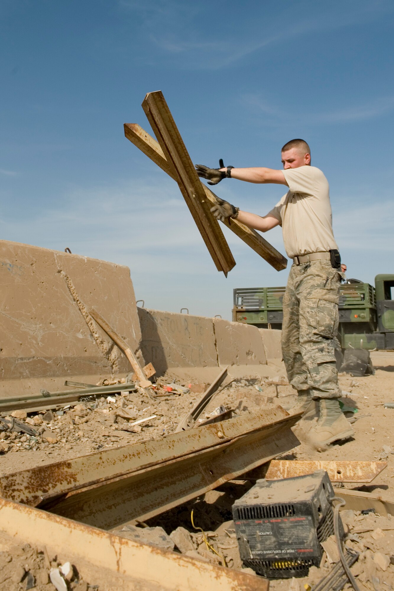 SATHER AIR BASE, Iraq -- Senior Airman Justin McGhee, 447th Expeditionary Security Forces Squadron member, throws pieces of scrap metal into a temporary dump site March 19. The collection point was set up in conjunction with "Operation Clean Sweep," which was an effort to reduce bulk trash on base in anticipation of relocating forces at the end of the year. Airman McGhee is deployed from the178th Security Forces Squadron, Springfield, Ohio, and is a native of Greenville, Ohio. (U.S. Air Force photo by Staff Sgt. Levi Riendeau)
