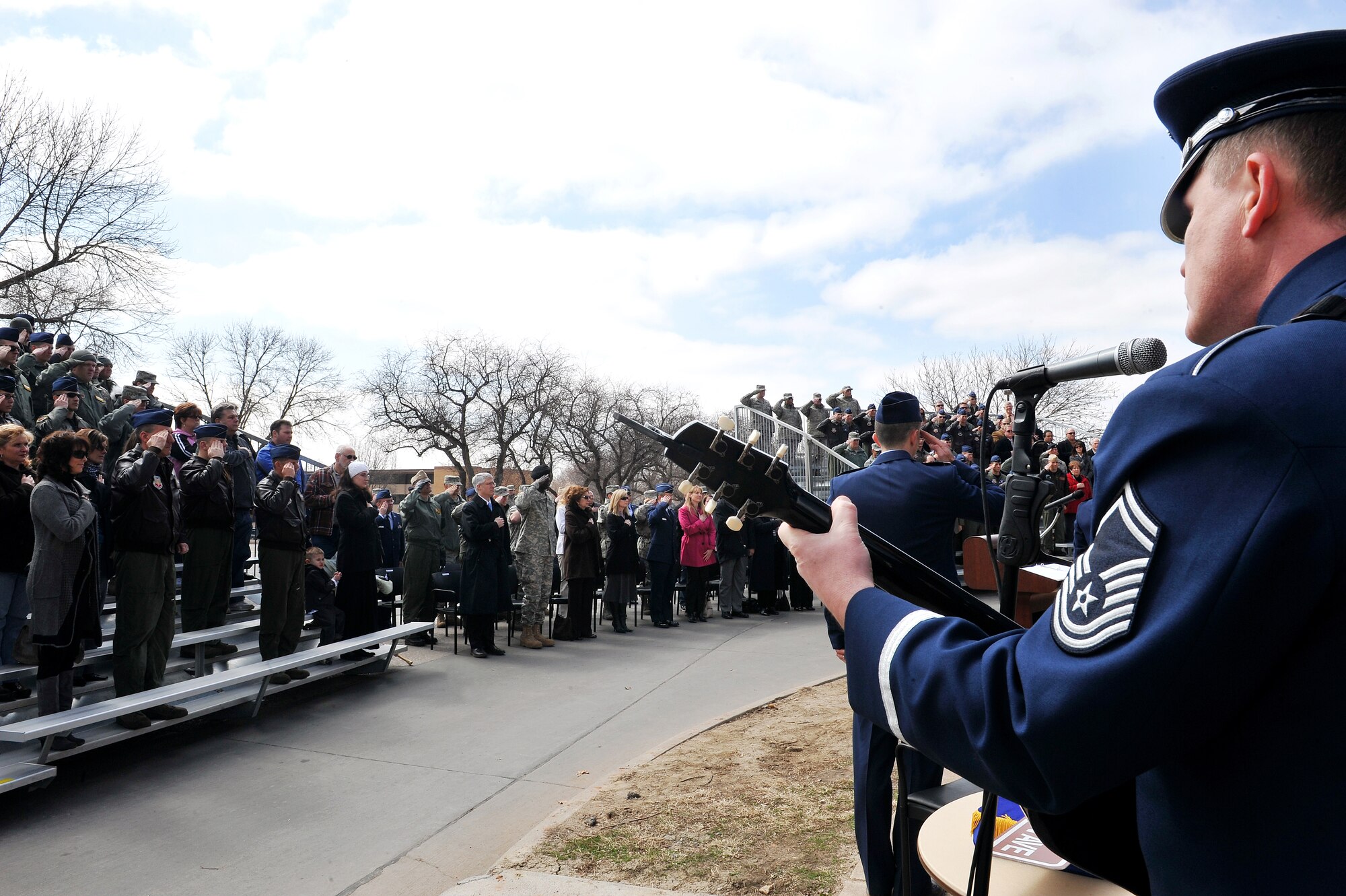 OFFUTT AIR FORCE BASE, Neb. - Team Offutt members and others from various agencies salute the American flag while Senior Master Sgt. Jimmy Weber, a guitarist with the Heartland of America Band, sings the National Anthem during a road rededication ceremony on the corner of SAC Boulevard and now Stratton Avenue here March 24. U.S. Air Force Photo by Charles Haymond