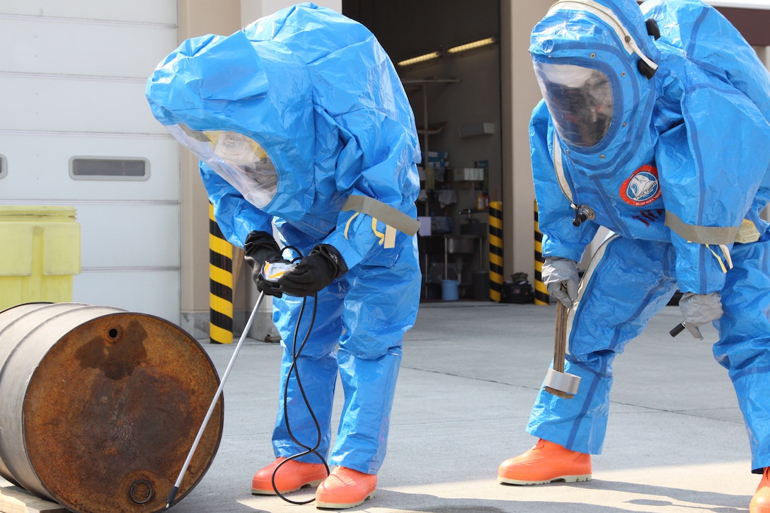 Two students from the Hazardous Materials Technicians Course test a leaking barrel for toxic chemicals and attempt to stop the leak at the Iwakuni Fire station March 30. Marines and station firefighters went through 12 stations of practical application that taught them how to deal with different hazardous chemicals and prevent harm. The course required 80 training hours to complete.