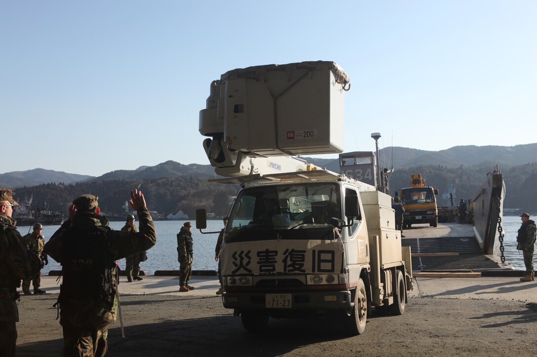 Sailors with Amphibious Squadron 11 direct Japanese utility repair vehicles into a U.S. Navy landing craft at the dock here, March 27.  The 31st Marine Expeditionary Unit and Amphibious Squadron 11 picked up the vehicles from the port here and delivered food, water, comfort items and the vehicles to residents on the isolated island of Oshima.  The island of Oshima has been cut off from the mainland since the earthquake and tsunami March 11.  U.S. Navy landing craft were used in the operation, demonstrating the MEU’s expeditionary capabilities in ship-to-shore amphibious operations. Marines and Sailors of the 31st MEU are conducting humanitarian aid and disaster relief missions in northeast Japan assisting the Japanese Self Defense Forces in their ongoing operations.