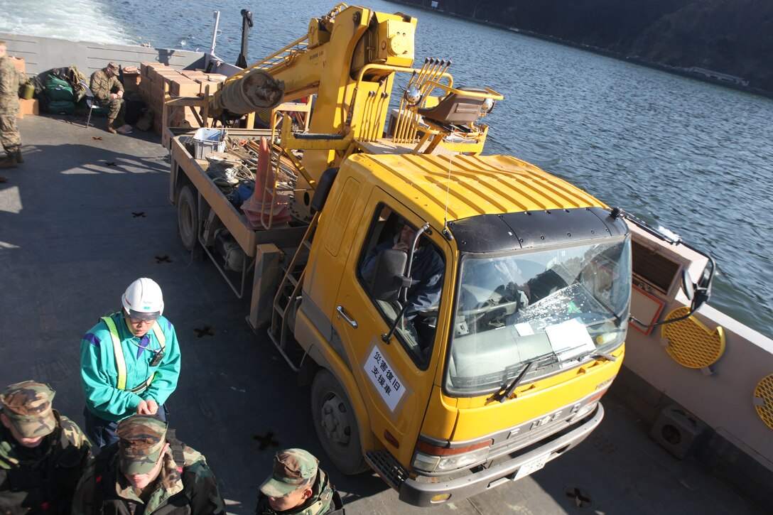 Japanese utility repair personnel and vehicles aboard a U.S. Navy landing craft head for the island of Oshima, March 27.  The 31st Marine Expeditionary Unit and Amphibious Squadron 11 picked up the vehicles from the port here and delivered food, water, comfort items and the vehicles to residents on the isolated island.  The island of Oshima has been cut off from the mainland since the earthquake and tsunami March 11.  The operation demonstrated the MEU’s expeditionary capabilities in ship-to-shore amphibious operations. Marines and Sailors of the 31st MEU are conducting humanitarian aid and disaster relief missions in northeast Japan assisting the Japanese Self Defense Forces in their ongoing operations.