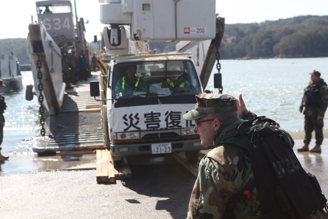 A U.S. Navy sailor directs a Japanese utility repair vehicle off a U.S. Navy landing craft docked here, March 27.  The 31st Marine Expeditionary Unit and Amphibious Squadron 11 picked up Japanese utility repair vehicles from the port in Kessenuma and delivered food, water, comfort items and the vehicles to residents on this isolated island.  The island of Oshima has been cut off from the mainland since the earthquake and tsunami March 11.  The operation demonstrated the MEU’s expeditionary capabilities in ship-to-shore amphibious operations. Marines and Sailors of the 31st MEU are conducting humanitarian aid and disaster relief missions in northeast Japan assisting the Japanese Self Defense Forces in their ongoing operations.