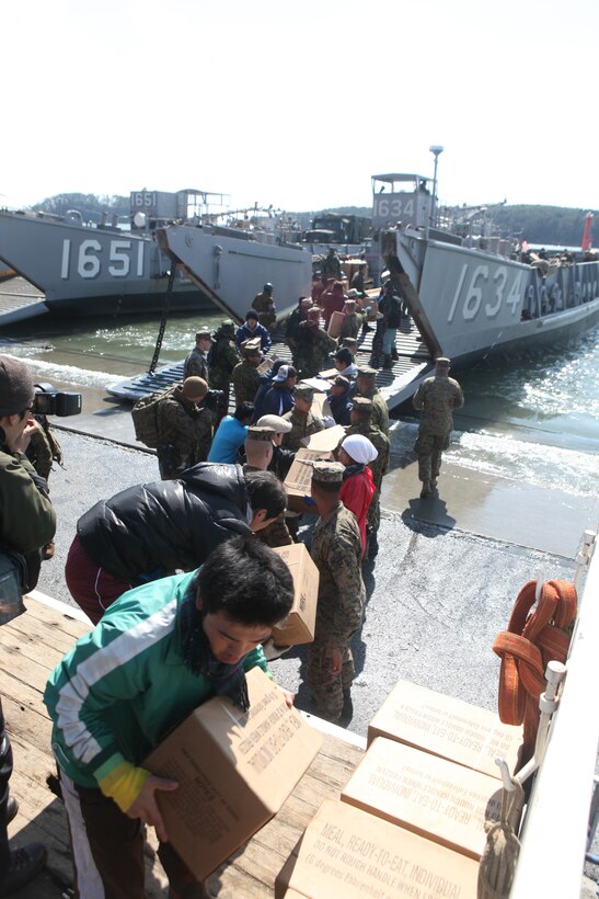 Marines of the 31st Marine Expeditionary Unit, Sailors with Amphibious Squadron 11, Japanese Ground Self Defense Forces, and local citizens unload food and water from a U.S. Navy landing craft, March 27.  The 31st MEU and PHIBRON-11 picked up Japanese utility repair vehicles from the port in Kessenuma and delivered food, water, comfort items and the vehicles to residents on this isolated island.  The island of Oshima has been cut off from the mainland since the earthquake and tsunami March 11.  The operation demonstrated the MEU’s expeditionary capabilities in ship-to-shore amphibious operations. Marines and Sailors of the 31st MEU are conducting humanitarian aid and disaster relief missions in northeast Japan assisting the Japanese Self Defense Forces in their ongoing operations.