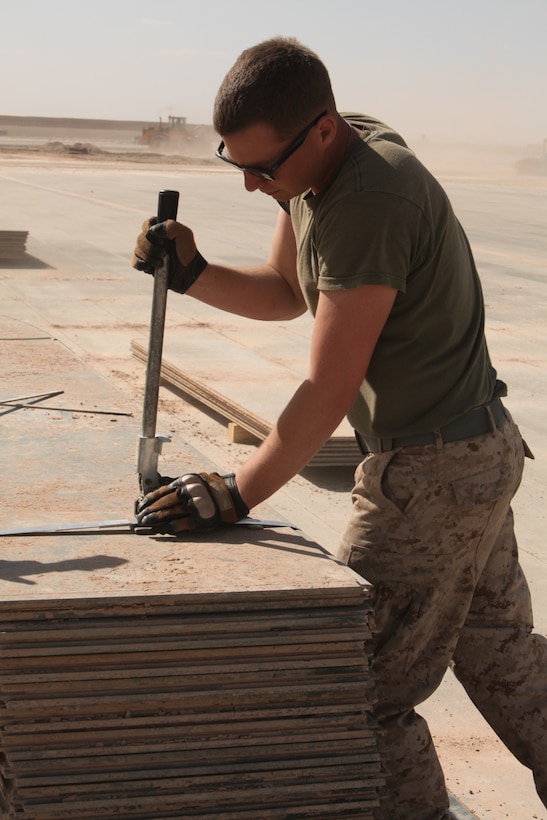 Cpl. Michael J. Devlin, an aircraft rescue and firefighting Marine with MWSS-272, secures pieces of aluminum matting together after they are removed from an inactive flight line on Camp Bastion, Afghanistan, March 29. Once the aluminum matting is removed a permanent runway will be constructed in its place. The Marines of MWSS-272 will move more than 3 million square feet of matting over the next several months as they complete the job. MWSS-272 is deployed out of Marine Corps Air Station New River, N.C. in support of 2nd Marine Aircraft Wing (Forward).