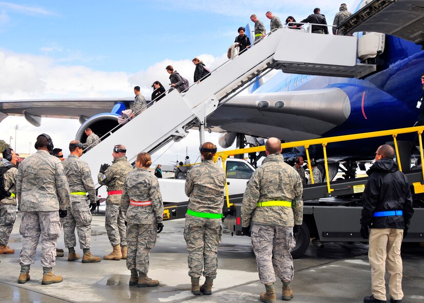 U.S. Air Force personnel wait to assist military families as they exit an aircraft arriving from Japan during Operation Pacific Passage operations on March 25, 2011, at Travis Air Force Base, Calif. Operation Pacific Passage gives military families the opportunity to voluntarily relocate from Japan to a safe haven in the U.S. in order to conserve Japanese resources. (U.S. Navy Photo/Mass Communication Specialist 2nd Class Eddie Harrison)