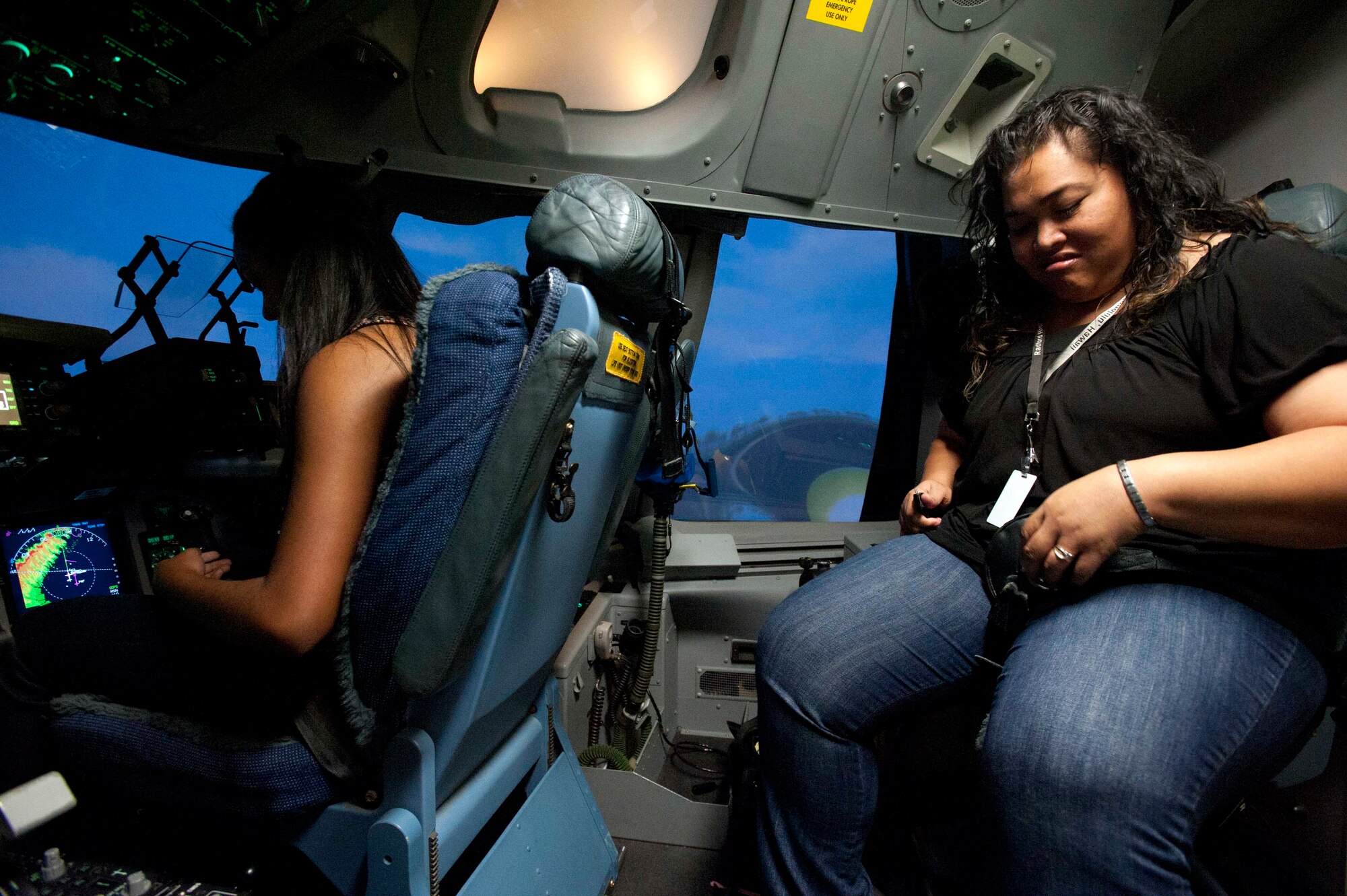 Amanda Nance (left), a Radford High School student and Iva Hunt, a RHS paraeducator, strap in for a flight in the C-17 flight simulator Mar. 24 at Joint Base Pearl Harbor-Hickam, Hawaii. During the visit, the RHS students visited various locations on base including the C-17 Operations building, C-17 simulator, fitness center, and the child development center. (U.S. Air Force photo by Staff Sgt. Nathan Allen)
