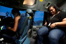 Amanda Nance (left), a Radford High School student and Iva Hunt, a RHS paraeducator, strap in for a flight in the C-17 flight simulator Mar. 24 at Joint Base Pearl Harbor-Hickam, Hawaii. During the visit, the RHS students visited various locations on base including the C-17 Operations building, C-17 simulator, fitness center, and the child development center. (U.S. Air Force photo by Staff Sgt. Nathan Allen)