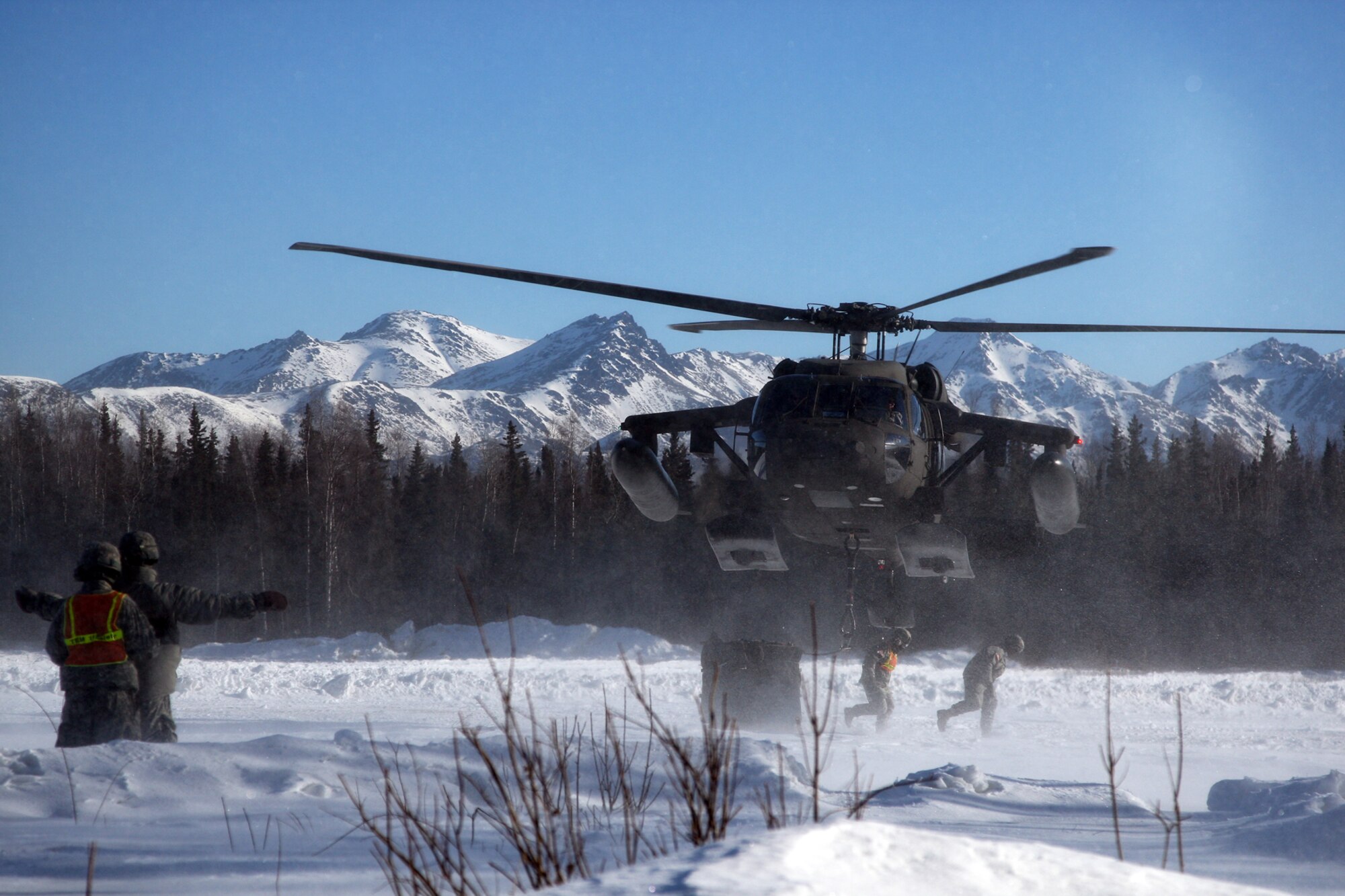 Soldiers clear the LZ after cargo is secured to the UH-60 Bkackhawk.  The Blackhawk is a single-engine, single main rotor helicopter used to transport personnel, supplies, and equipment.  It has a cargo hook capacity of 8,000 pounds.