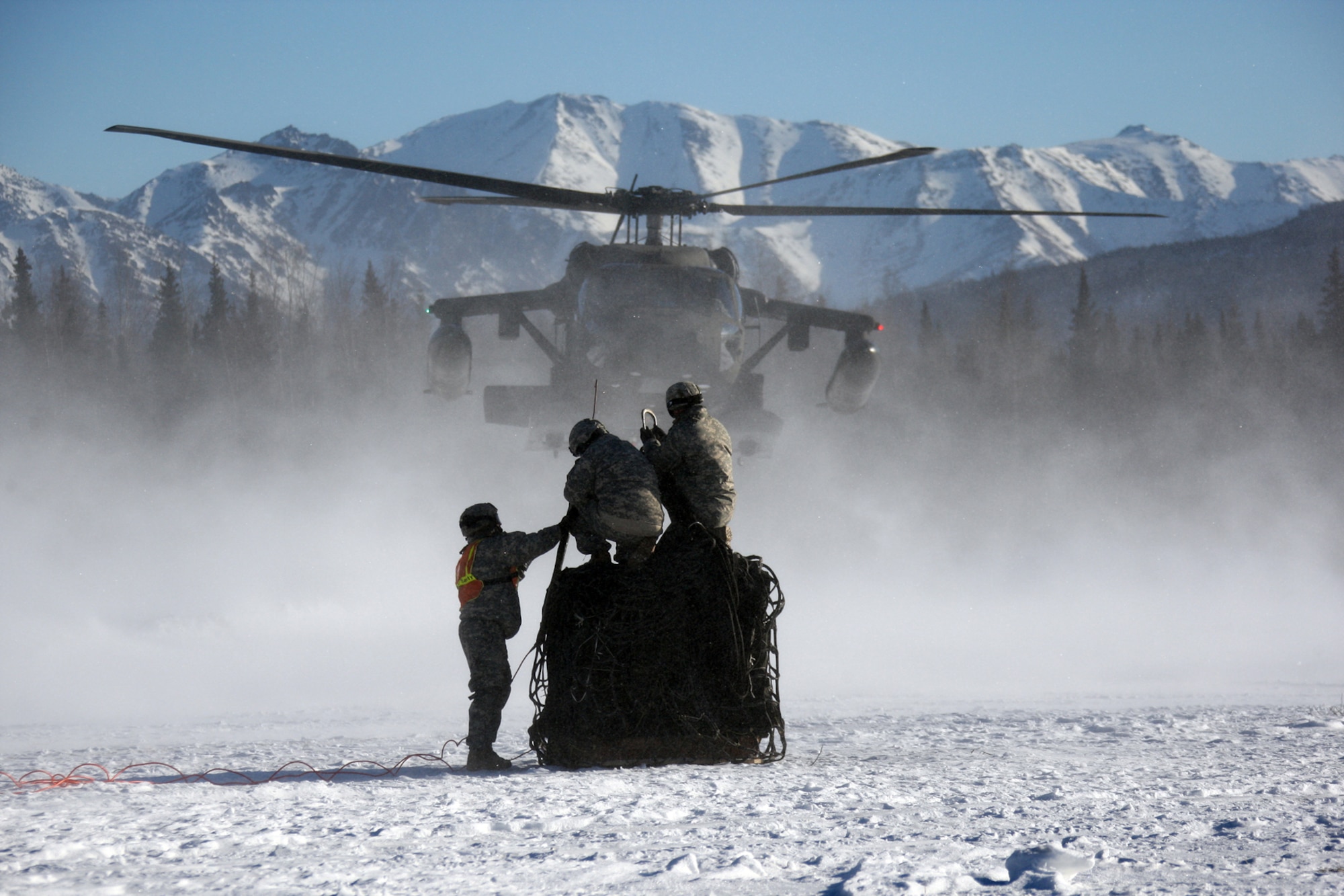 Soldiers stand ready to hook up cargo to an inbound UH-60 Blackwawk.  As an aerial delivery unit, the Riggers of the 4th Quartermaster Detachment stand ready to rig 50 short tons of supplies or equipment within twenty four hours, while also demonstrating extreme proficiency in light pack operations.
