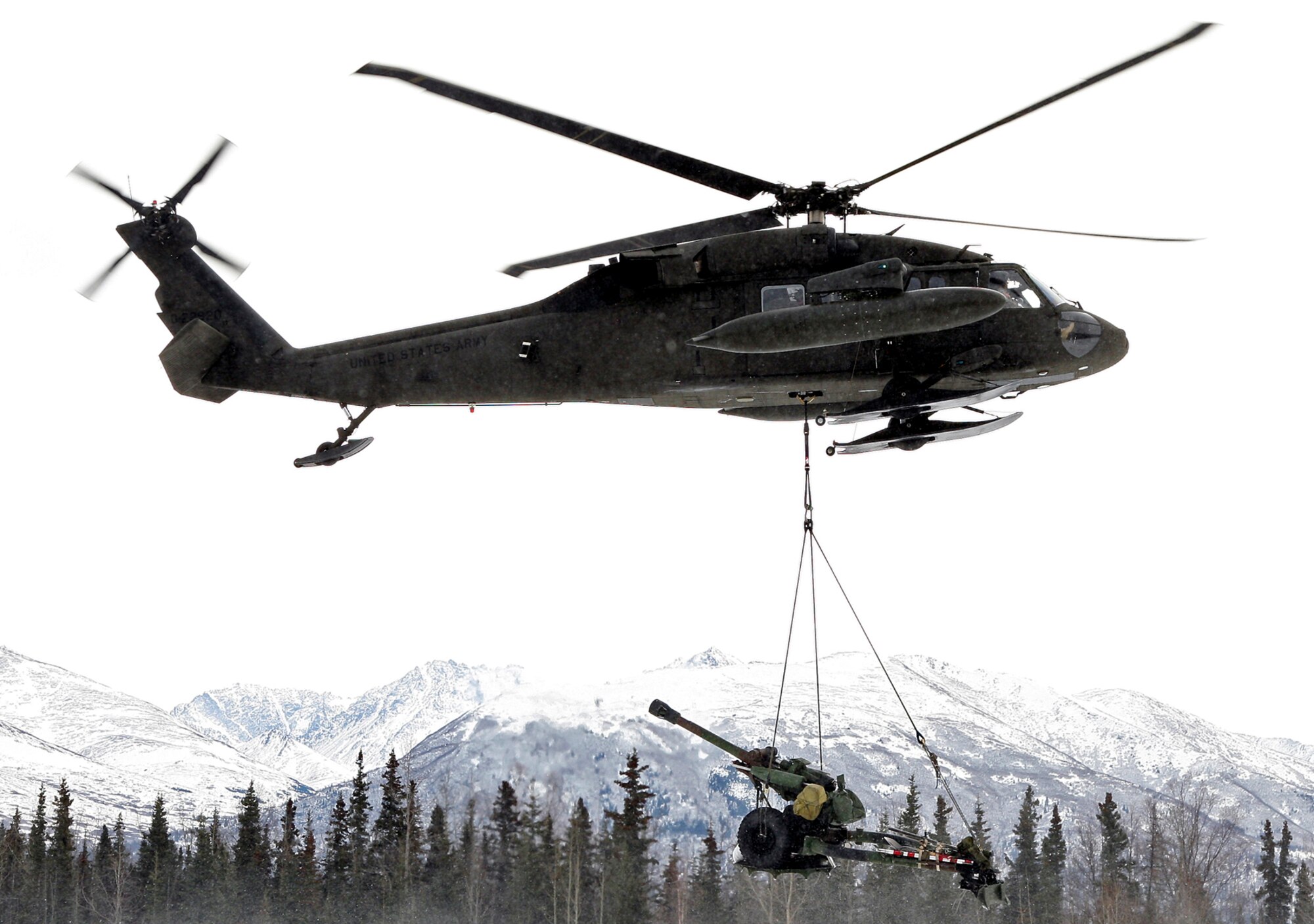 Securely rigged, an Alaska Army National Guard UH-60 Blackhawk airlifts a M119A2 Howitzer at the completion of an air assault raid at LZ Ranger.