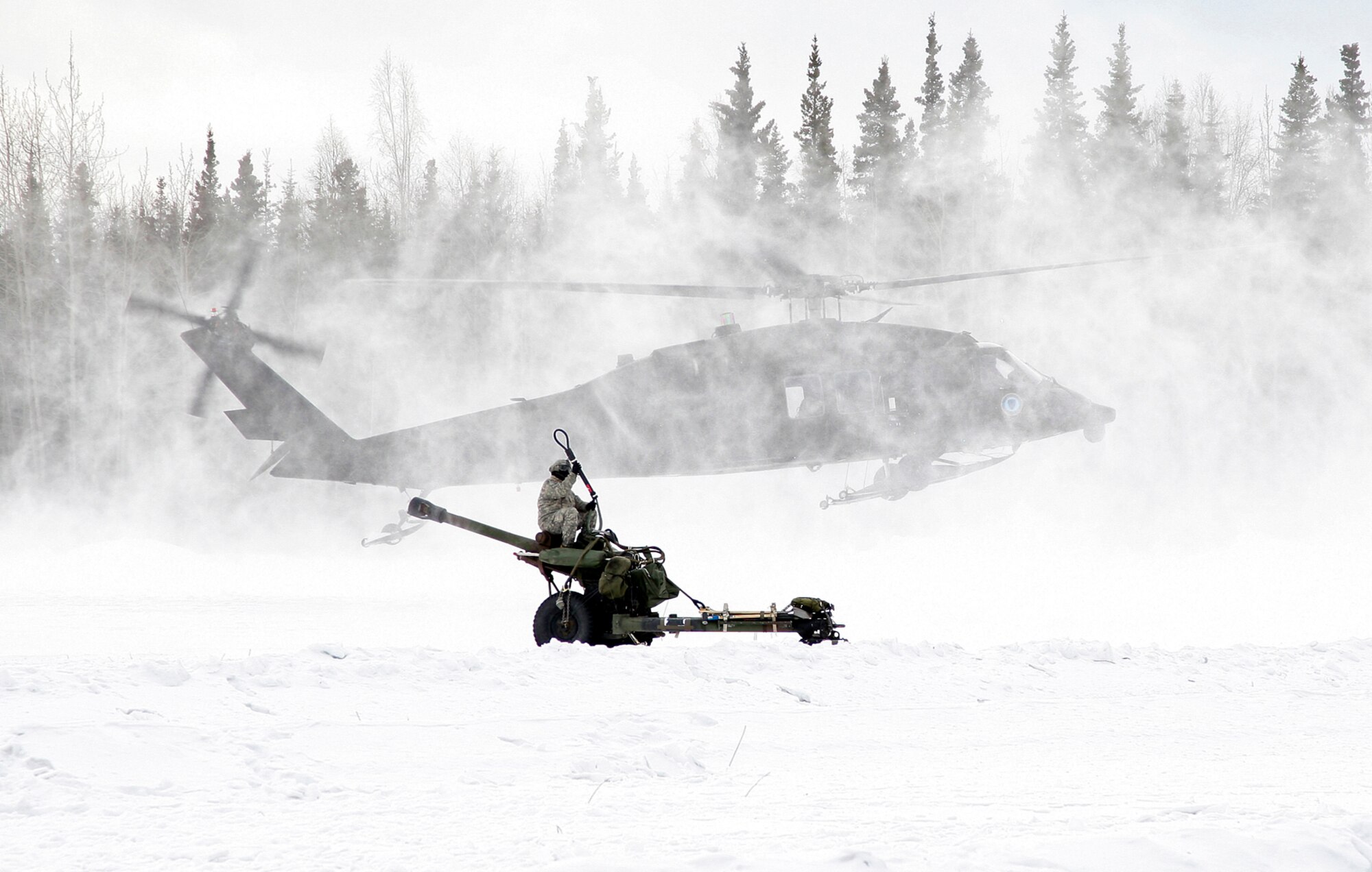 A Soldier from Alpha Battery 2-377 PFAR prepares to hook up a M119A2 Howitzer to an Alaska Army National Guard UH-60 Blackhawk for an air assault raid.