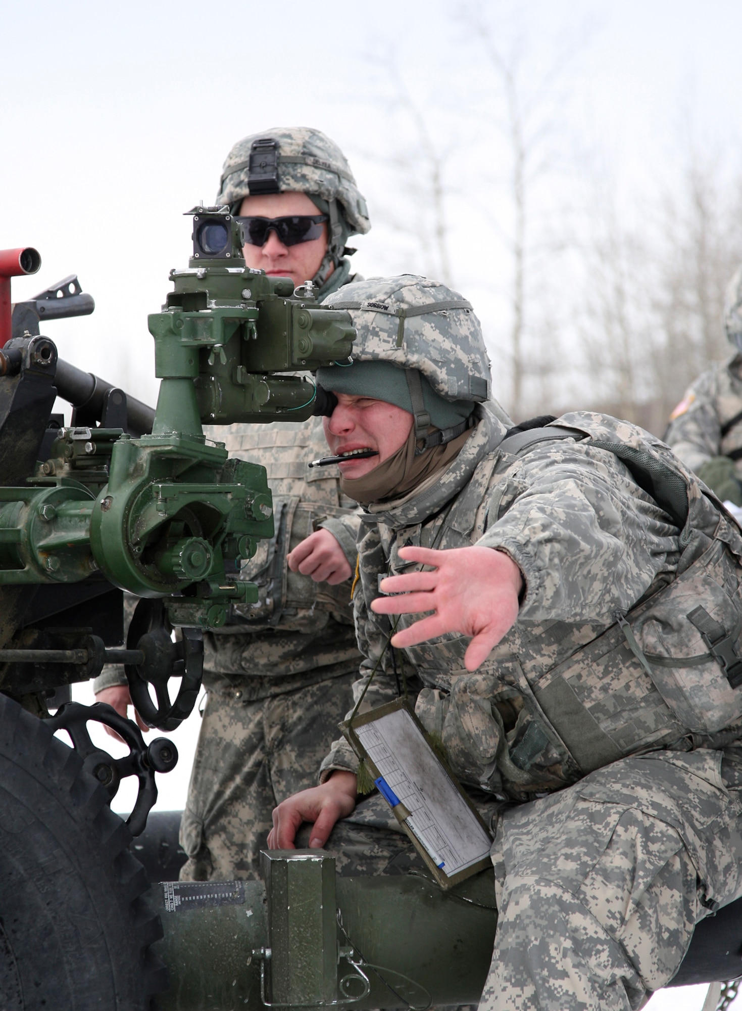 Spec. Benjamin Delyea (standing) watches as gunner Sgt. Christopher Sorrow emplaces a aiming reference prior to firing the M119A2 Howitzer.