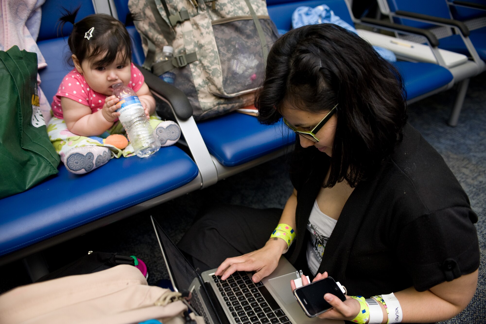 Eight-month-old Iliana Sierra wathces her motherr, Betzabeth Sierra, attempt to contact family members after the pair arrived at Travis Air Force Base, Calif., on March 25 from Japan. Following the earthquake and tsunami that hit Japan on March 11, hundreds of family members from military bases in Japan voluntarily relocated to the United States after radiation from crippled Japanese nuclear energy plants was detected in some areas. (U.S Air Force photo/Ken Wright)