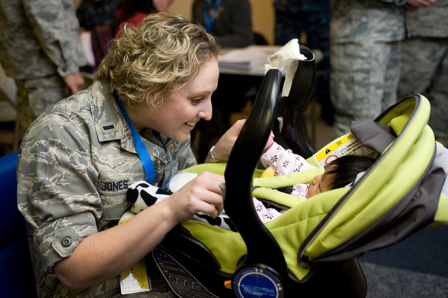 First Lt. Fawn Jones, a social worker from the 60th Medical Group, coos at a baby at Travis Air Force Base, Calif., on March 28, 2011. The child and her mother arrived at Travis following the earthquake and tsunami that hit Japan on March 11, 2011. In support of Operation Pacific Passage, Travis personnel assisted more than 2,600 military dependents as they voluntarily relocated to the United States. (U.S. Air Force Photo/Ken Wright)