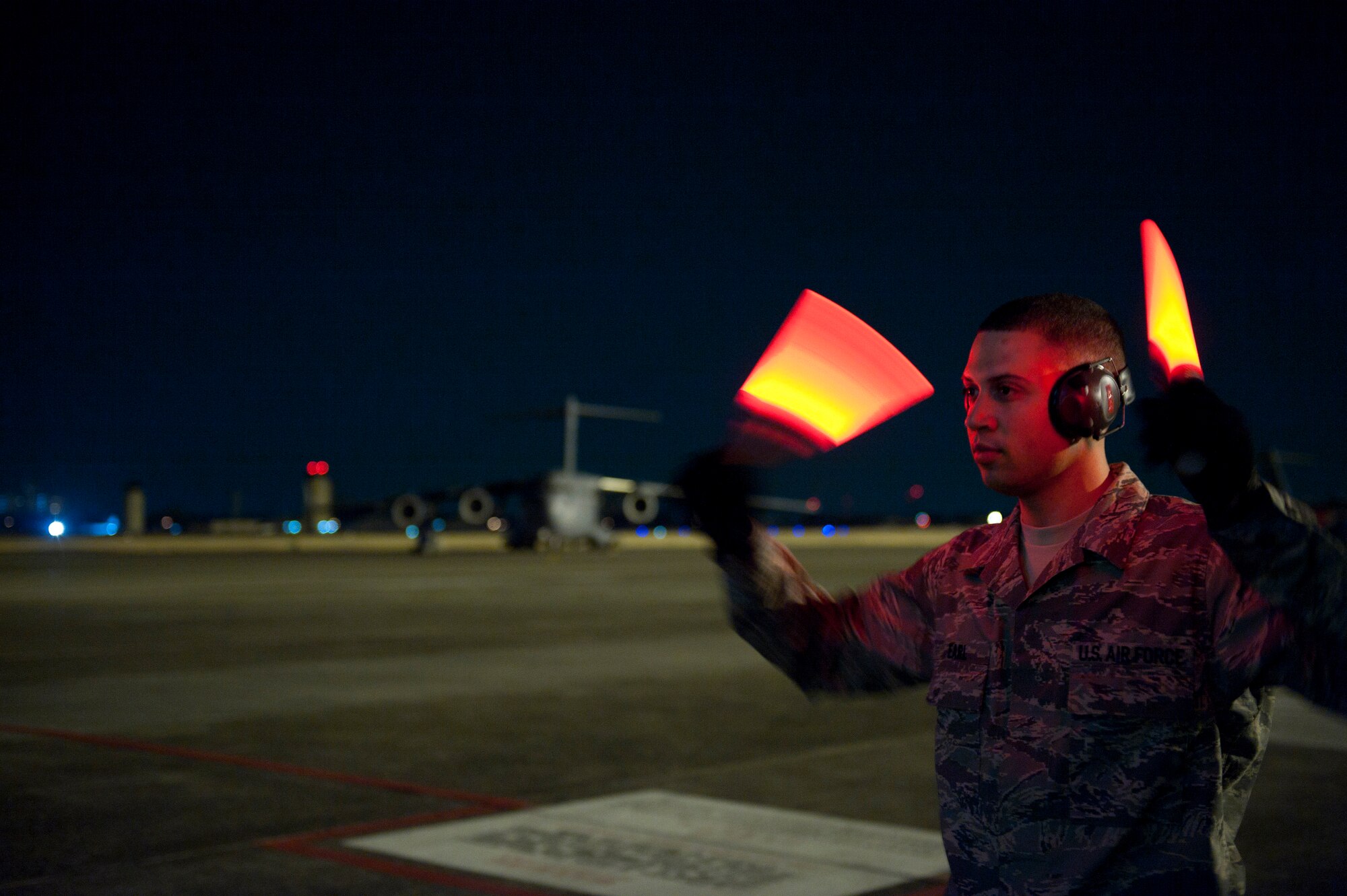 YOKOTA AIR BASE, Japan -- Staff Sgt. Mychal Earl, 730th Air Mobility Squadron ramp services supervisor, directs the off-loading of a C-17 Globemaster III here March 29. The C-17 carried water pumps and hoses to help stabilize the nuclear power plant in Japan in support of Operation Tomodachi. (U.S. Air Force photo/Staff Sgt. Chad C. Strohmeyer)