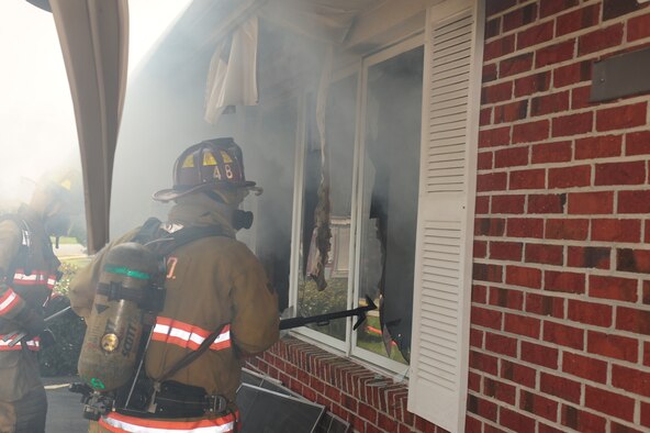 SEYMOUR JOHNSON AIR FORCE BASE, N.C. – Vanden Lee breaks a window for additional ventilation during a controlled burn in a house scheduled for demolition here March 25, 2011. Lee is a firefighter with the Goldsboro Fire Department and hails from Goldsboro. (U.S. Air Force photo/Senior Airman Rae Perry) (RELEASED)