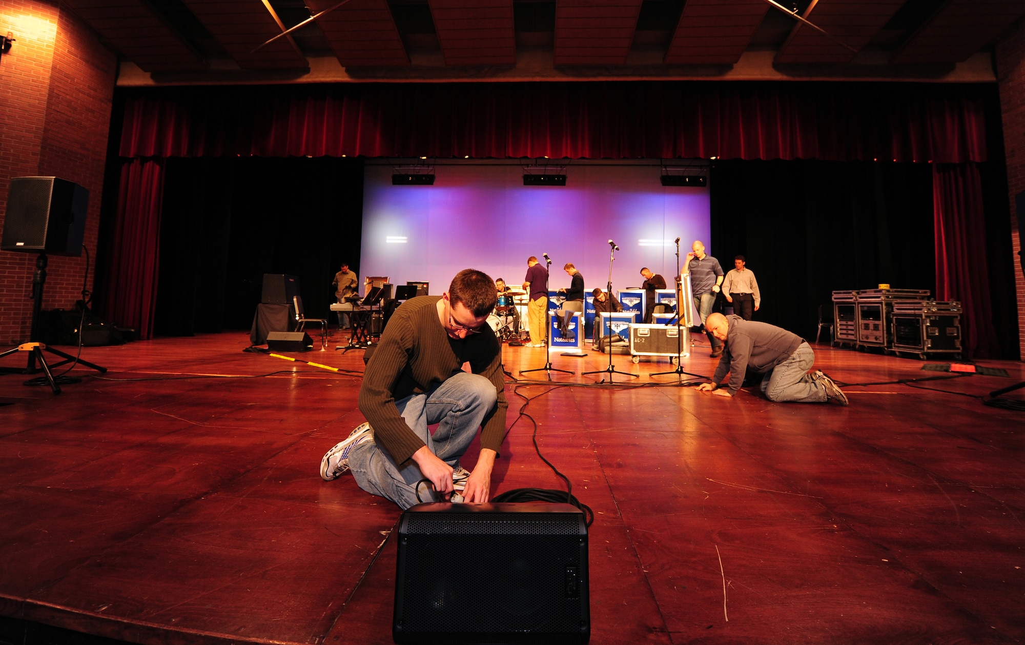 OFFUTT AIR FORCE BASE, Neb. - Senior Airman Greg Phlugh, saxophone with the Heartland of America Band's Noteables jazz ensemble, runs cables to the stage speakers as part of setting up at Ames High School's auditorium in Ames, Iowa, March 27. Jazz fans filled into a 600-seat auditorium to see the Air Force ensemble perform. U.S. Air Force photo by Josh Plueger (released)
