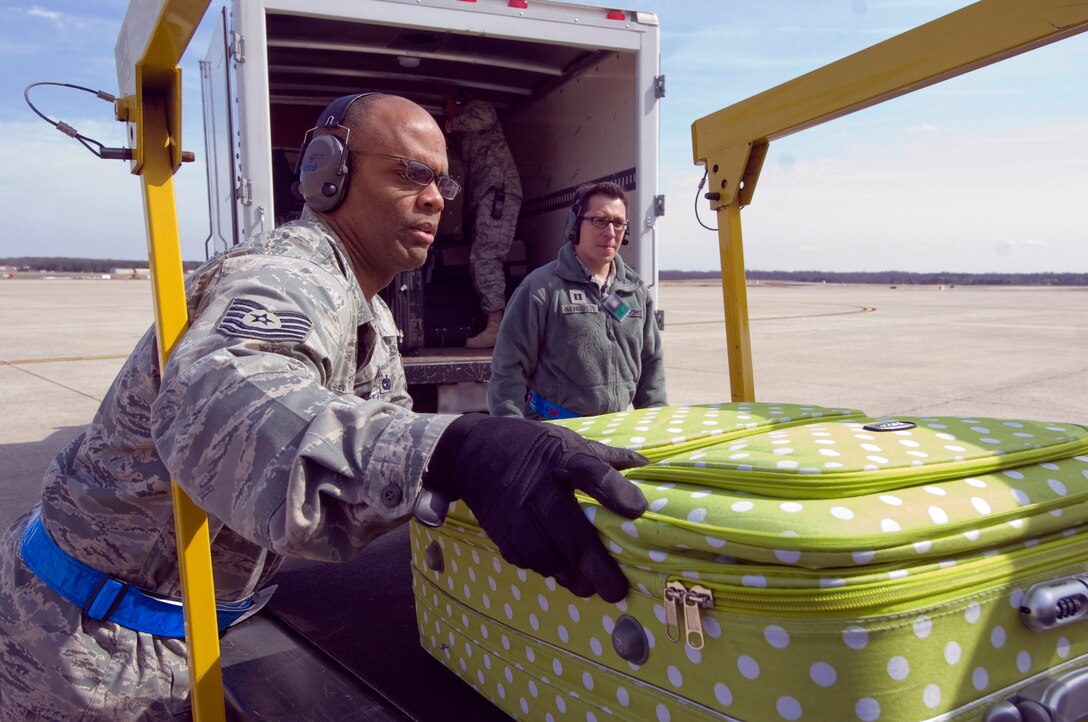 Technical Sgt. Clarence Williams, 89th Aerial Port Squadron passenger service agent, off loads luggage from a conveyor belt while Capt. Eric Navarratte,  89 APS operations officer, stands by to help on the flightline March 28.  (Photo by Bobby Jones)