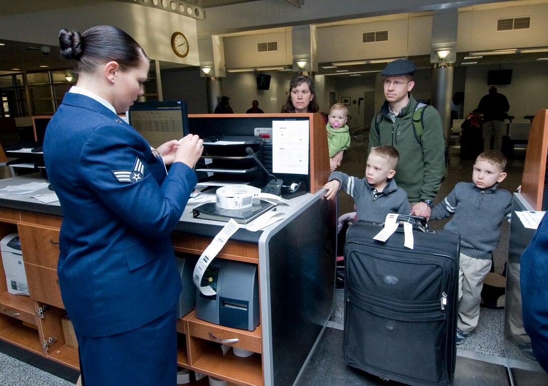Senior Airman Mary Long, left,  89th Aerial Port Squadron aircraft services specialist, tags luggage for Maj. Jeff Gallagher, a physics student at the Air Force Institute of Technology and his family during a Space Available flight from Andrews March  28. (Photo by Bobby Jones)