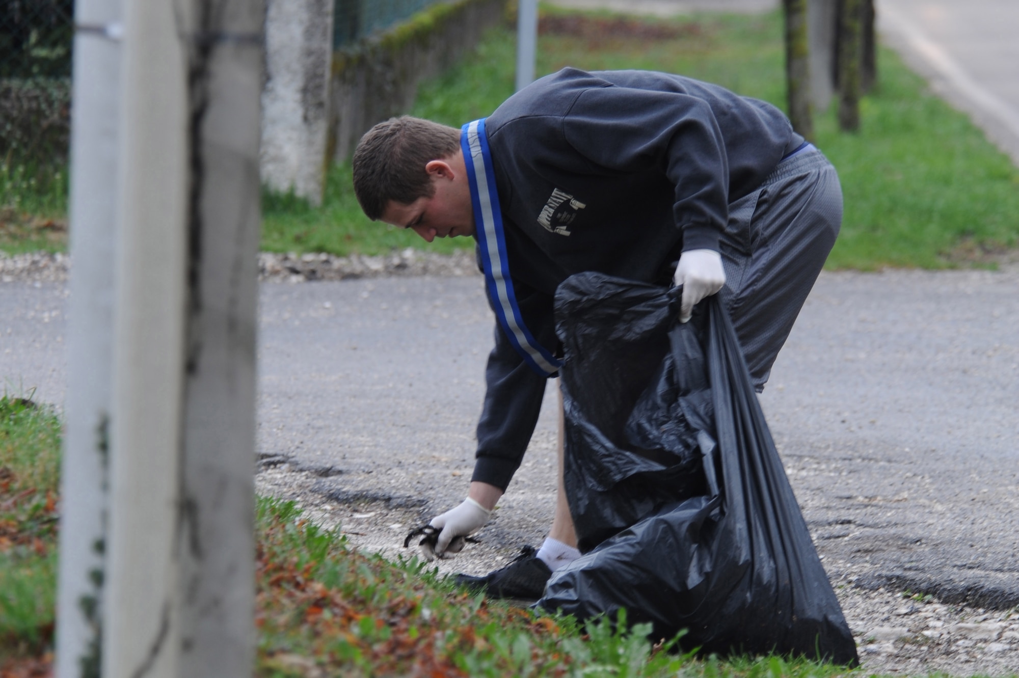 Airman 1st Class Jacob Paul, 8th Air Support Operations Squadron terminal attack control party member, collects trash along the side of the road as part of the 8th ASOS community beautification project, Mar 27. Eighteen volunteers cleaned roads from Area F to Area 1, and those leading from Area F to the mountain highway, collecting 25 bags of refuse.  (U.S. Air Force photo/ Staff Sgt. Nadine Y. Barclay)