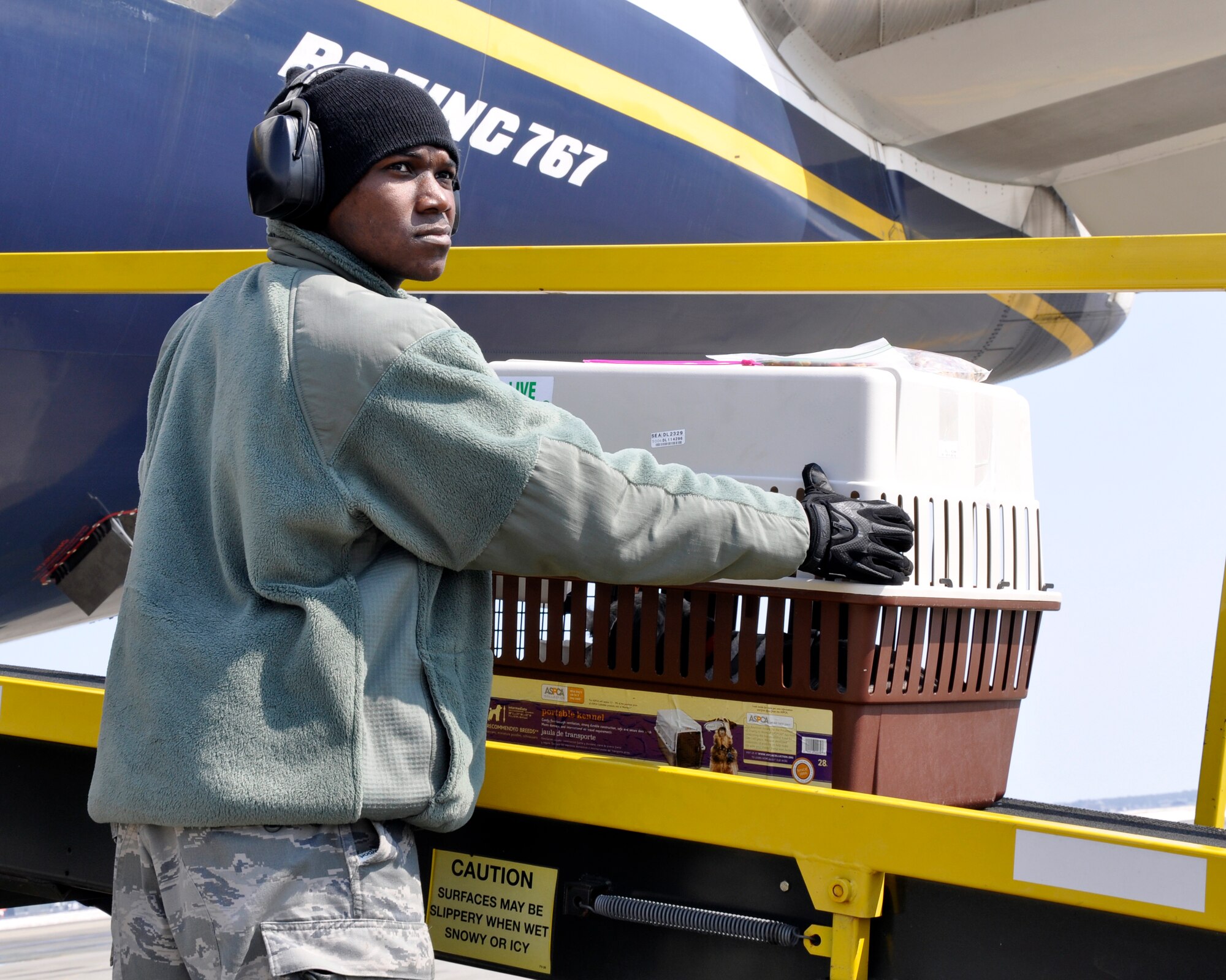 MISAWA AIR BASE, Japan-- U.S. Air Force Airman 1st Class Casey Jones, 621st Contingency Response Wing aerial porter assigned to McGuire Air Force Base, moves a dog crate on board a commercial aircraft on the flightline at Misawa Air Base, Japan, March 26, 2011. The aircraft was carrying several Misawa civilians back to the United States as part of the voluntary departure after the earthquake and tsunami that devastated Japan March 11, 2011. (U.S. Air Force photo by Senior Airman Joe W. McFadden / RELEASED) 