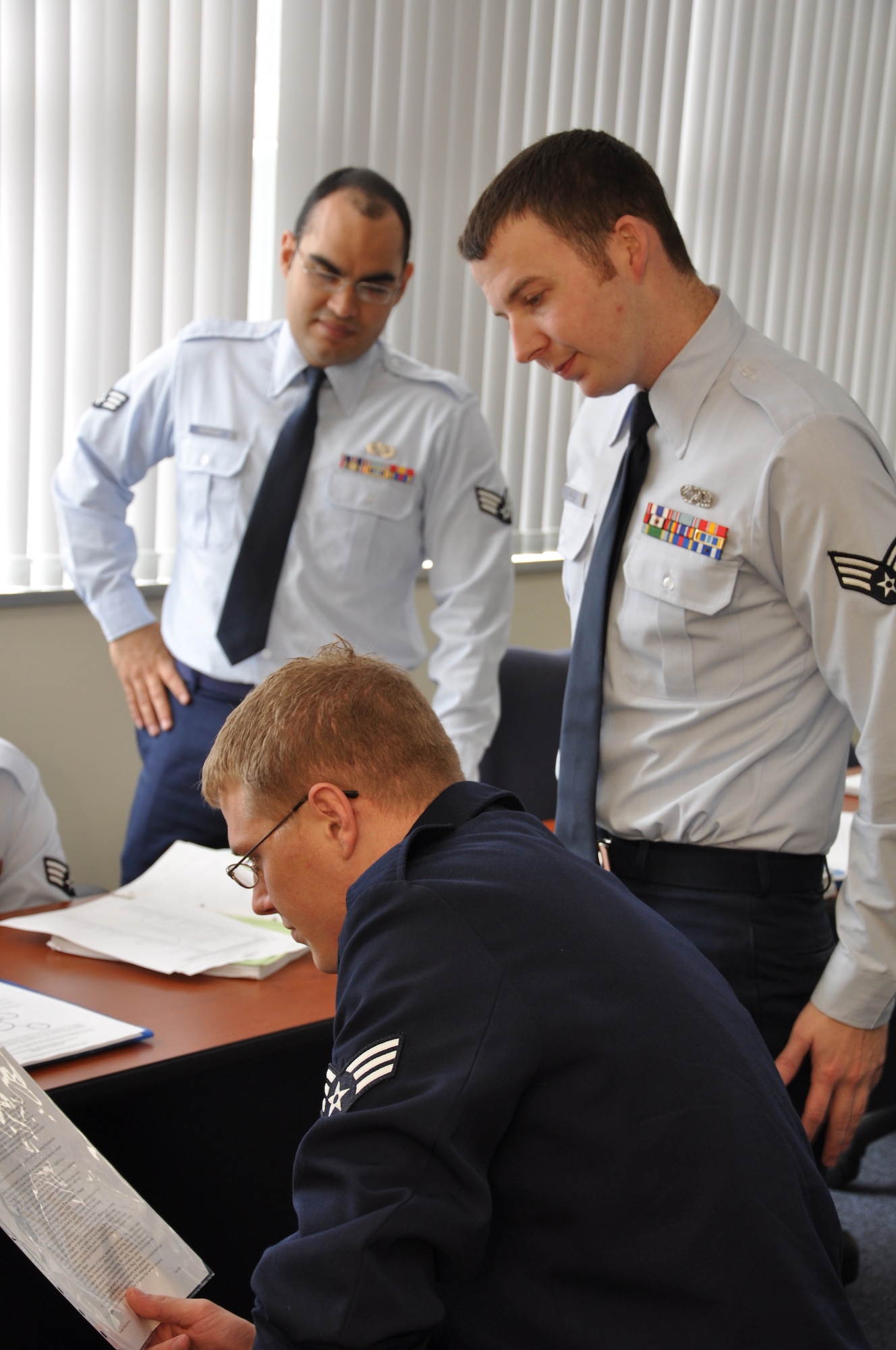 Kadena Airman Leadership School students Senior Airman Edward Rodriguez and Senior Airman Robert Rogers stand while Senior Airman Parker Bryant reviews a scenario dealing with interpersonal communication feedback, here March 13. The new Erwin Professional Military Education Center opened its doors for the first ALS and the Noncommissioned Officer Academy classes in the new facility earlier this month. (U.S. Air Force photo by Master Sgt. Geoff Robertson) 
