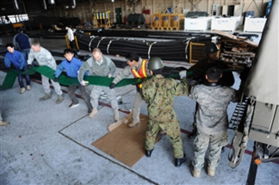 U.S. airmen, members of the Japan Ground Self-Defense Force and various Japanese civilian agencies load water hoses onto a truck at Yokota Air Base, Japan, for a water pumping station to be employed at the Fukushima Daiichi Nuclear Power Plant during Operation Tomodachi on March 26, 2011.  The Tokyo Electrical Power Company added an additional water pumping station to pump fresh water instead of seawater to cool the reactors at the damaged nuclear power facility with the help of the U.S. government and various other agencies.  As part of Operation Tomodachi, the U.S. military has humanitarian assistance capabilities positioned in the affected region supporting emergency relief efforts at the request of the Japanese government.  