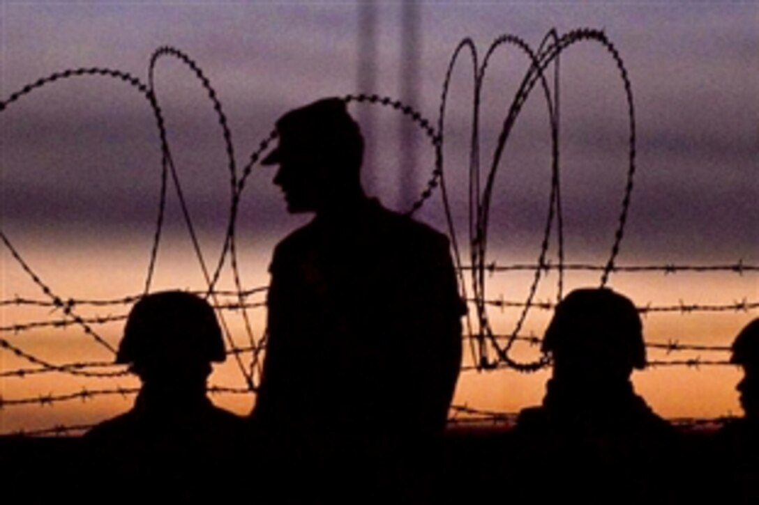 A group of International Security Assistance Force Regional Command soldiers talk at dusk while pulling security in Kandahar, Afghanistan, March 28, 2011. 