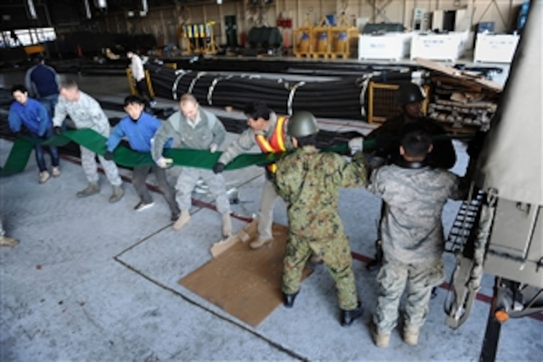 U.S. airmen, members of the Japan Ground Self-Defense Force and various Japanese civilian agencies load water hoses onto a truck at Yokota Air Base, Japan, for a water pumping station to be employed at the Fukushima Daiichi Nuclear Power Plant during Operation Tomodachi on March 26, 2011.  The Tokyo Electrical Power Company added an additional water pumping station to pump fresh water instead of seawater to cool the reactors at the damaged nuclear power facility with the help of the U.S. government and various other agencies.  As part of Operation Tomodachi, the U.S. military has humanitarian assistance capabilities positioned in the affected region supporting emergency relief efforts at the request of the Japanese government.  
