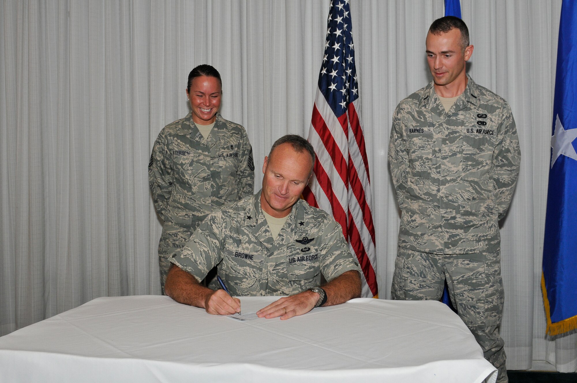 Brigadier Gen. James S. Browne signs a donation pledge form to kick off the Air Force Assistance Fund Campaign accompanied by Senior Master Sgt. Jody Petersen, 325th Medical Support Squadron assistant installation project officer and 1st Lt. Brett Barnes, 325th Contracting Squadron, installation project officer, March 29 at Horizons Community Center. (U.S. Air Force photo by Lisa Norman)

