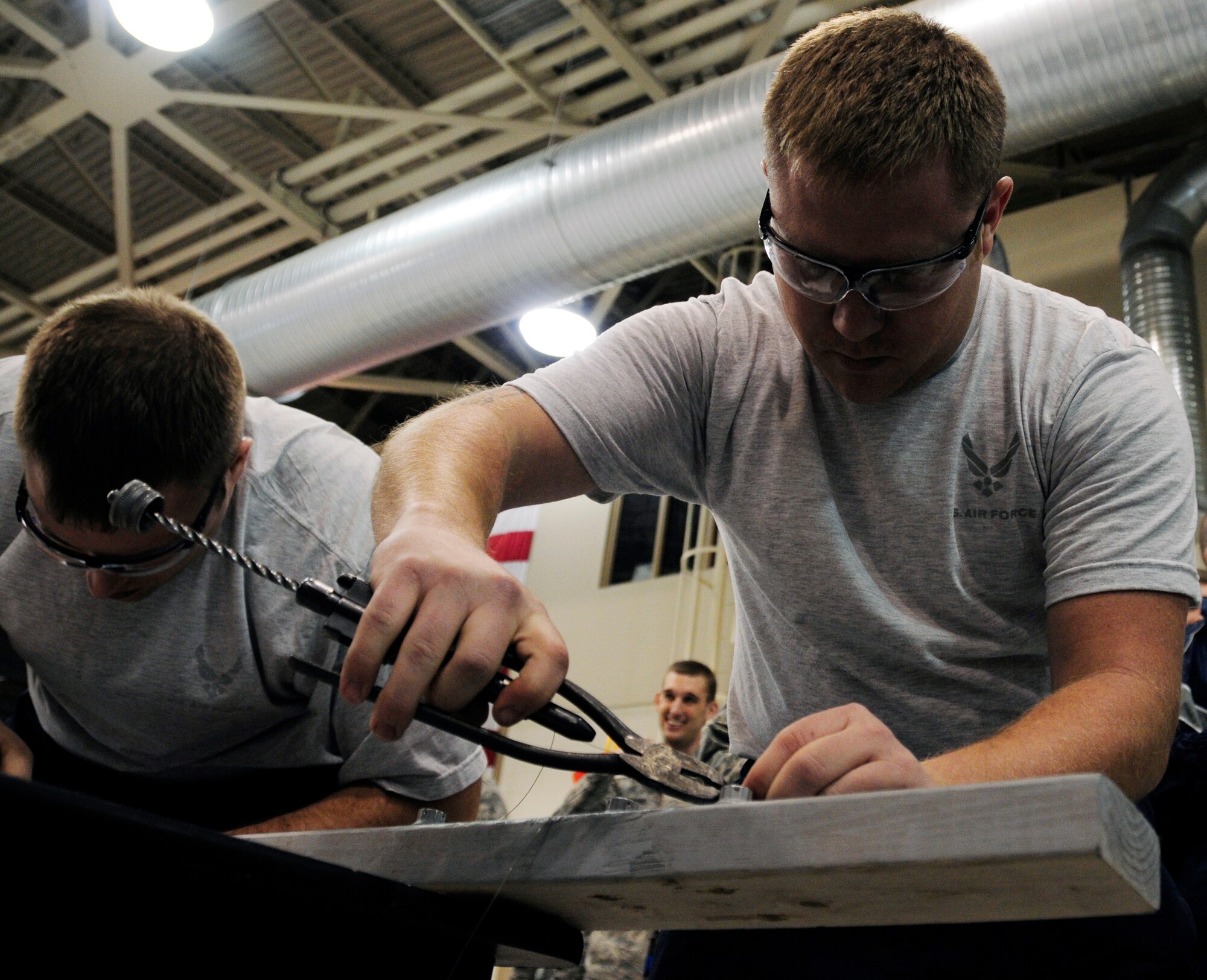 Airmen use safety wire pliers to tighten fasteners in a race against the clock March 25, 2011, Eielson Air Force Base, Alaska.  The safety wire race was one of many challenges at the 354th Maintenance Group olympics where Airmen demonstrated skills in technique and speed in common maintenance tasks.  (U.S. Air Force photo by/Airman 1st Class Yash Rojas)
