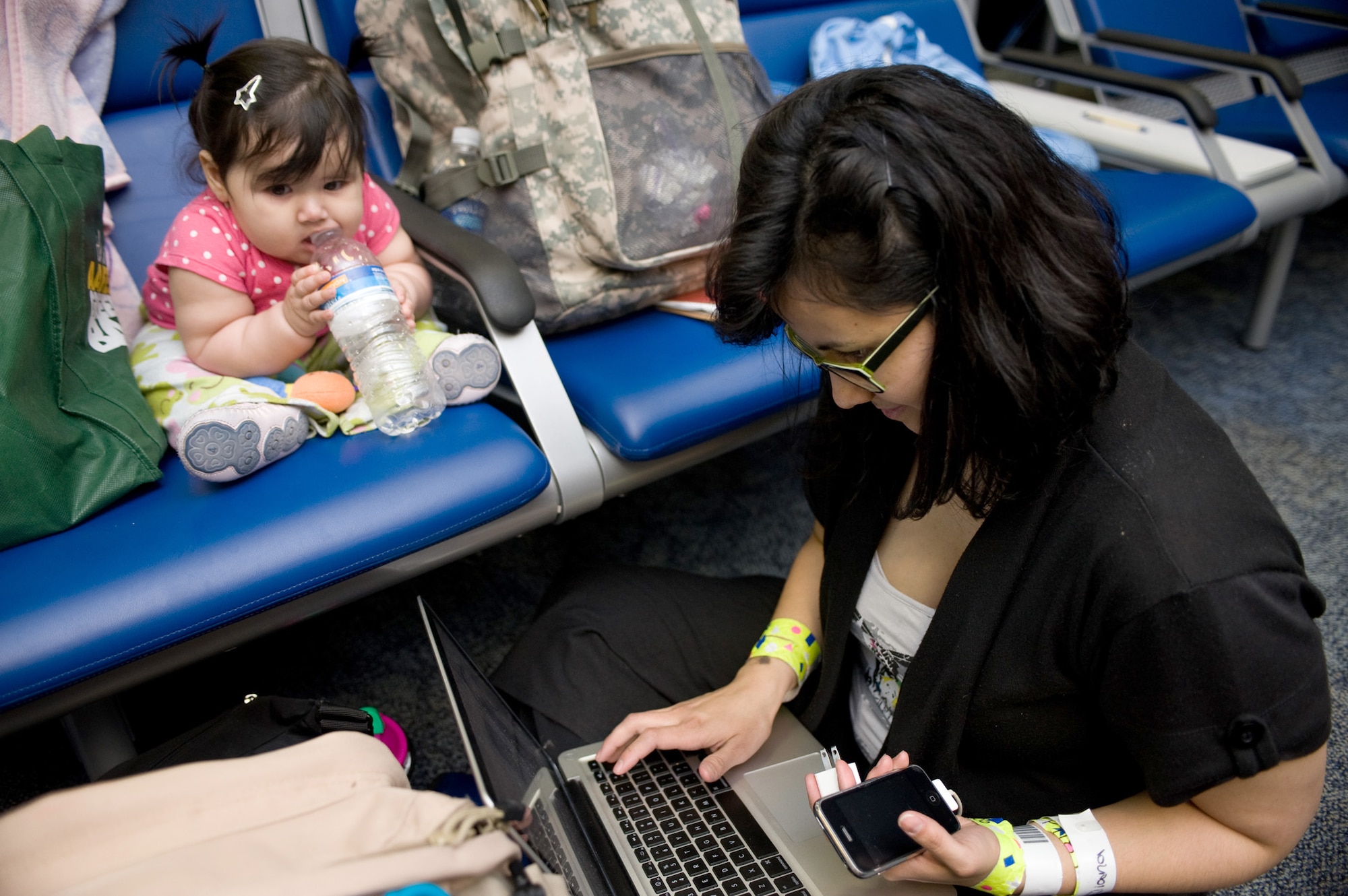 Eight-month-old Iliana Sierra watches as her mother, Betzabeth Sierra, attempts to contact family members after the pair arrived from Japan, March 25, 2011, at Travis Air Force Base, Calif. Following the earthquake and tsunami that hit Japan on March 11, hundreds of family members from military bases in Japan voluntarily relocated to the U.S. (U.S Air Force photo/Ken Wright)
