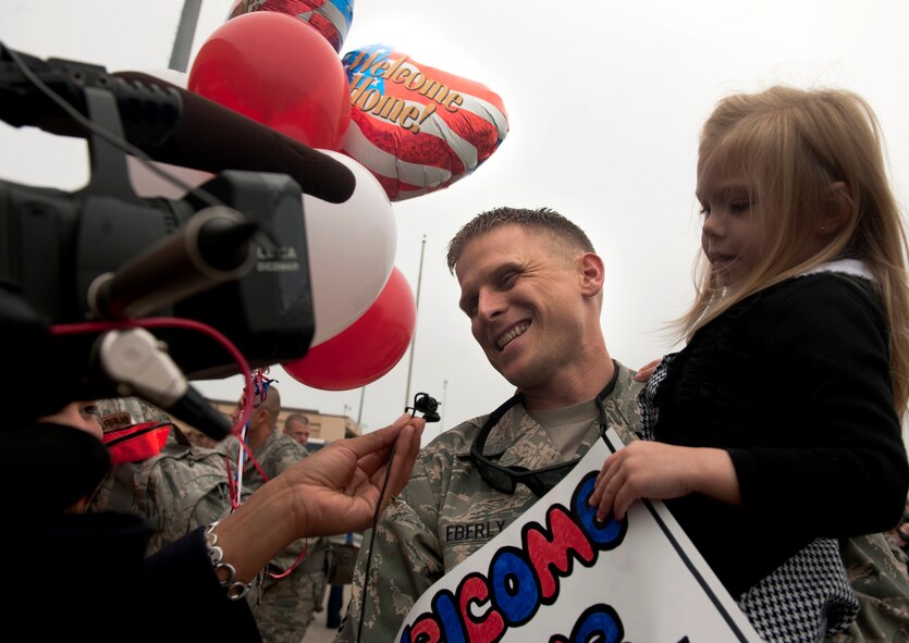 Master Sgt. Travis Eberly, 75th Fighter Squadron aircraft section chief, holds his daughter Makenzie while being interviewed by local media at Moody Air Force Base, Ga., March 29. Sergeant Eberly returned home after a six-month deployment to Kandahar, Afghanistan, and said the return was overwhelming. (U.S. Air Force photo/Airman 1st Class Joshua Green)(RELEASED)
