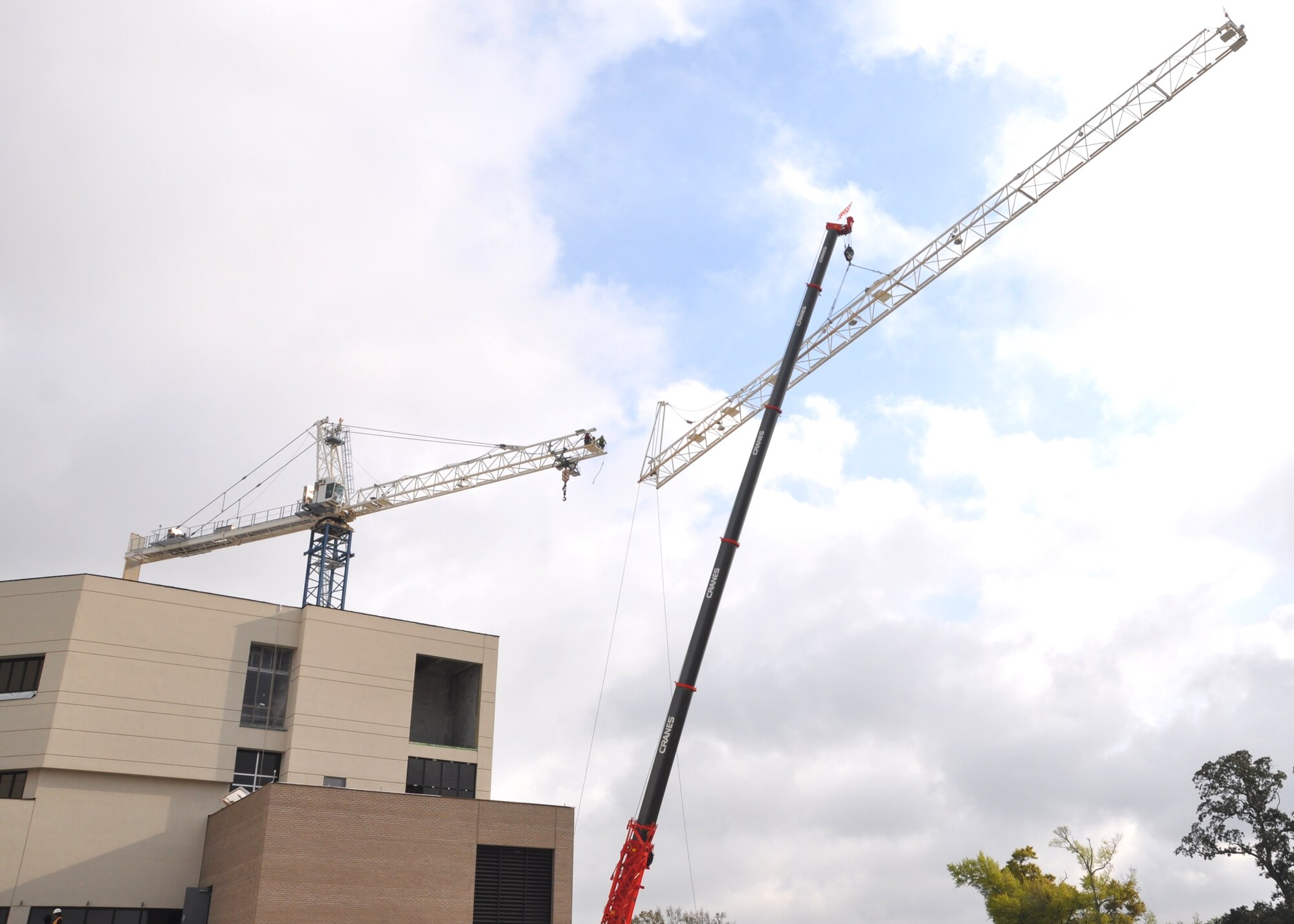 Workers from Phoenix Rigging and Erecting, Atlanta, dismantle the 81st Medical
Group Hospital Inpatient Tower construction crane March 22. The almost 150-foot tall structure had loomed over the site since February 2010. With work proceeding on the tower’s interior, the crane has served its purpose. To get construction materials to the tower’s four floors, “We will use the internal elevators starting in a couple of weeks,” said Yates Construction site supervisor John Horton. “In the meantime, we’ll use the stairs.”  The disassembly began with removal of the eight counterweights at the end of the boom. Then the workers took the boom apart section-by-section, with the operator’s capsule saved for last, before they dismantled the vertical portion. Mr.
Horton said the specially-made concrete base, which is below ground level, will
simply be covered over.  (U.S. Air Force photo by Steve Pivnick)