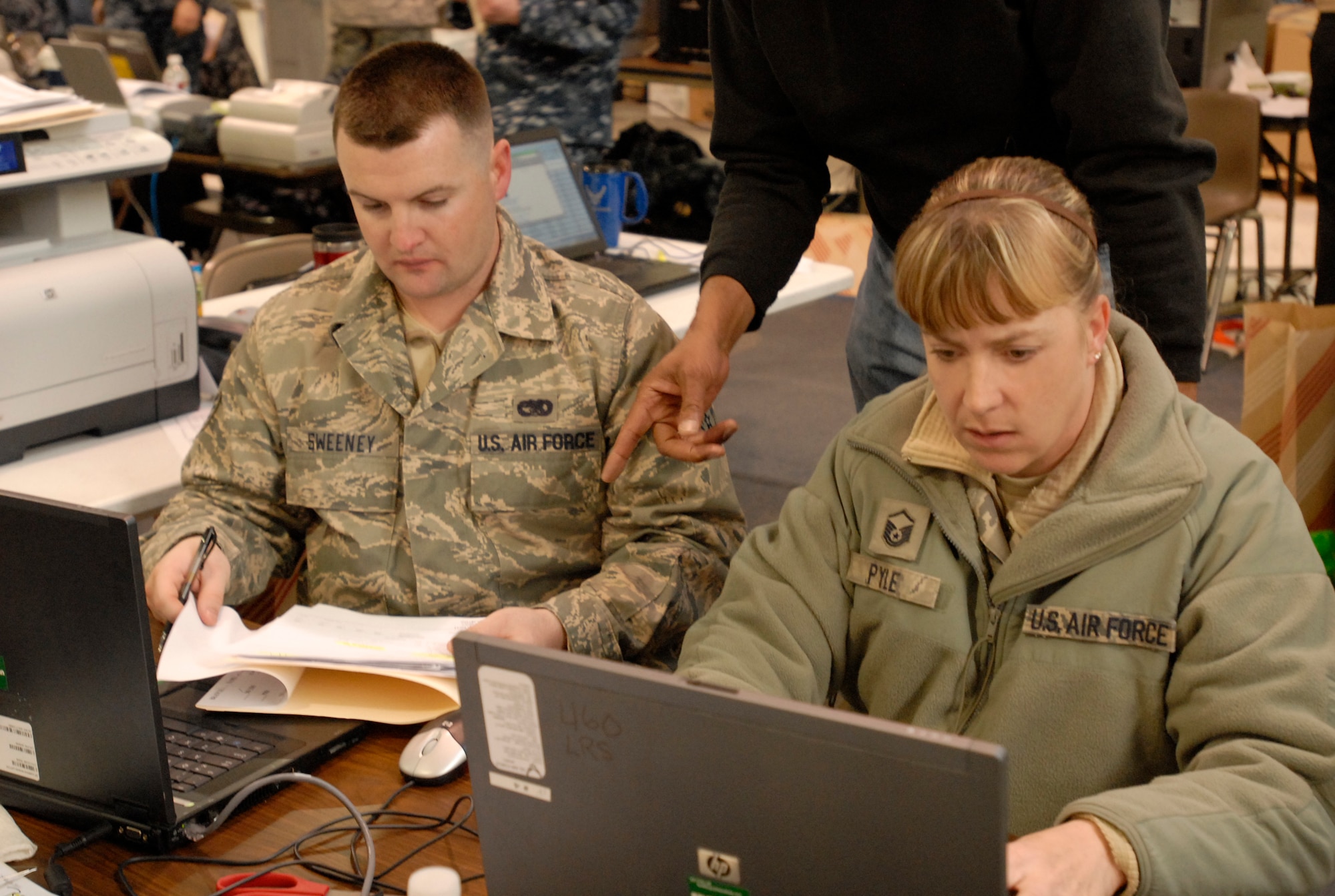 Master Sgt. Brenda Pyle and Staff Sgt. John Sweeney, 21st Logistics Readiness Squadron, work on processing flight information for incoming military families from Japan. Military family members were offered flights to return to their home of record following the March 11 earthquake in Japan while recovery efforts continue throughout the region. In all, 21st LRS personnel helped process more than 550 military families arriving through Denver International Airport March 23 to 25. (U. S. Air Force photo/Airman 1st Class Jessica Hines)