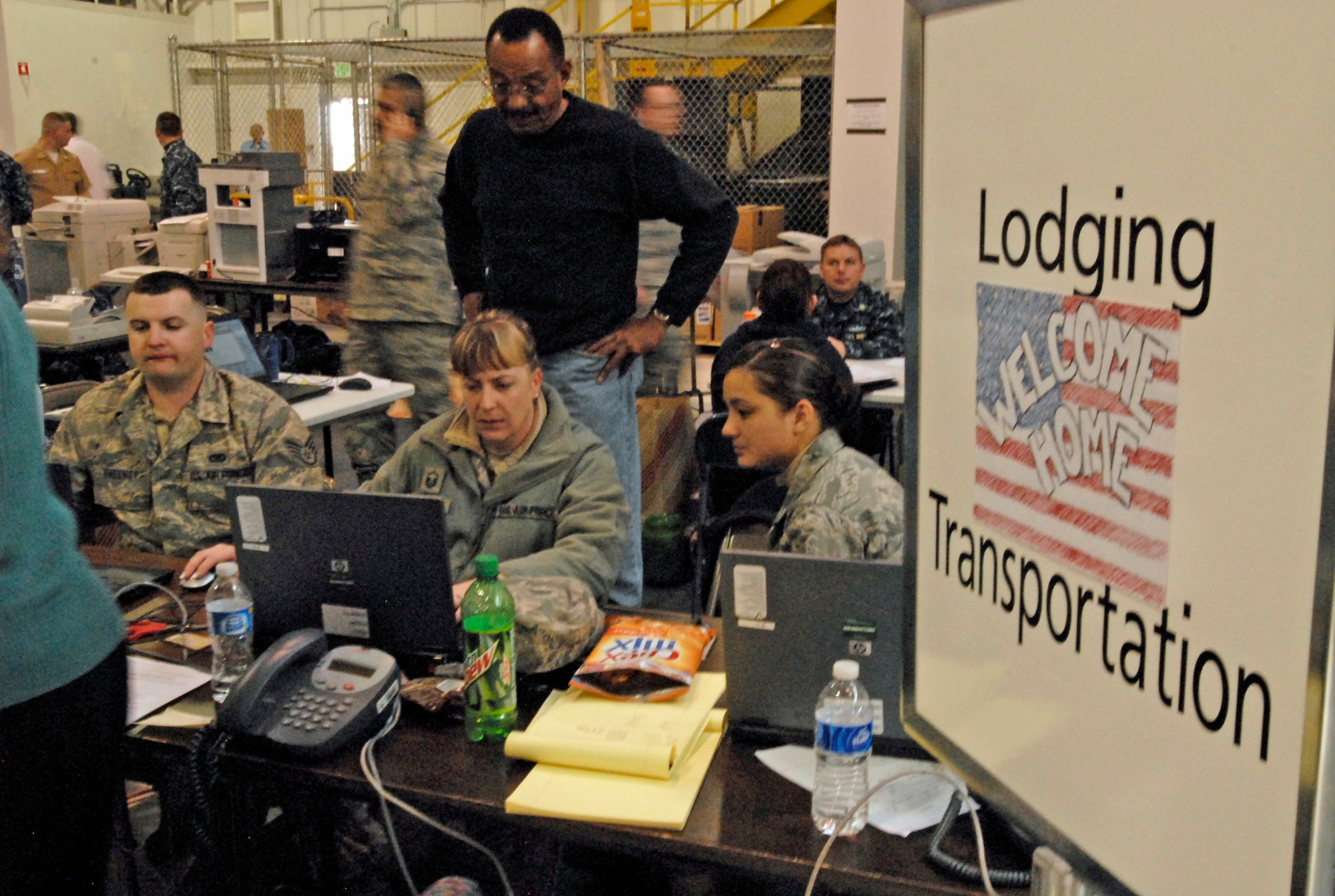 Staff Sgt. John Sweeney, Master Sgt. Brenda Pyle and Airman 1st Class Lisa Klevenberg, 21st Logistics Readiness Squadron, help process more than 550 military family members voluntarily leaving Japan after the March 11 earthquake there. A hangar near Denver International Airport was used as a processing area for the military families returning from Japan. Servicemembers from all branches came together to help provide support for the military families returning home from Japan. (U.S. Air Force photo/Airman 1st Class Jessica Hines)