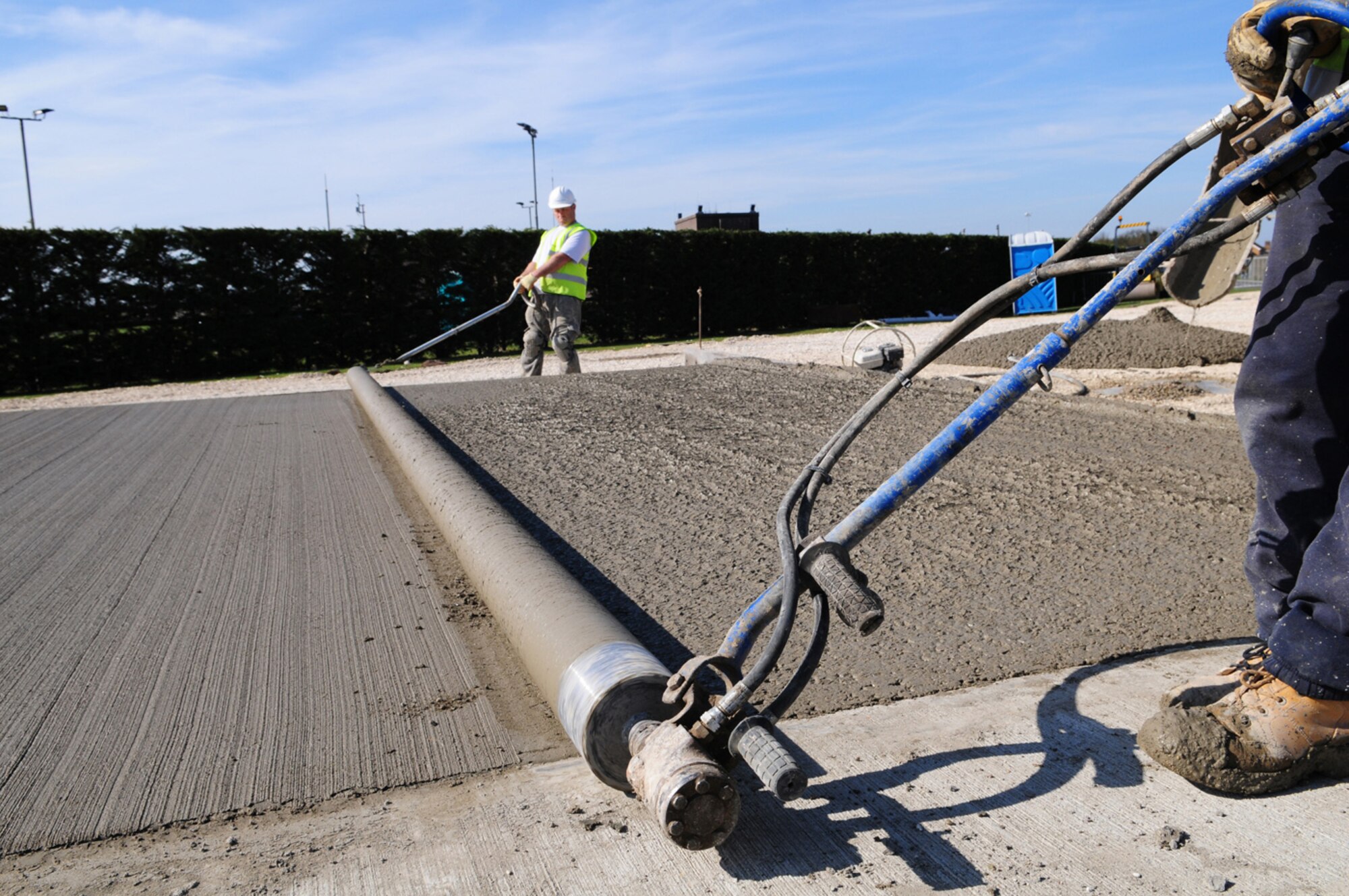 RAF MILDENHALL, England -- Paul Wiseman, left, and Peter Kent, both contractors, prepare to pull a razorback screed roller across wet, freshly-laid concrete to smooth it out and prepare for the next stage of the construction project March 24, 2011. The area is being turned into a concrete batching plant, allowing concrete to be mixed from scratch on RAF Mildenhall, rather than it being pre-mixed at a location off base and brought here on trucks. This will reduce the carbon footprint as well as save money. (U.S. Air Force photo/Karen Abeyasekere)