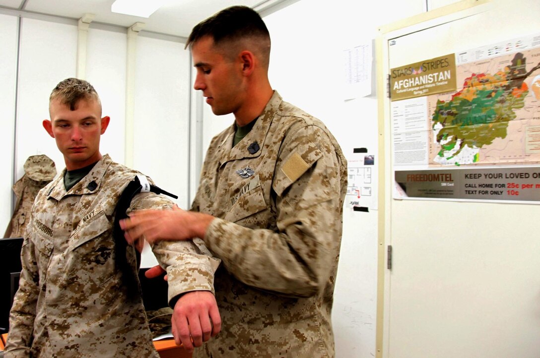 Petty Officer 2nd Class Matthew Hicks, a corpsman with II Marine Expeditionary Force (Forward), demonstrates the proper application of the newest combat action tourniquet.  One of the updated features on the CAT is the attached time band, used to record when the tourniquet was applied to the casualty.