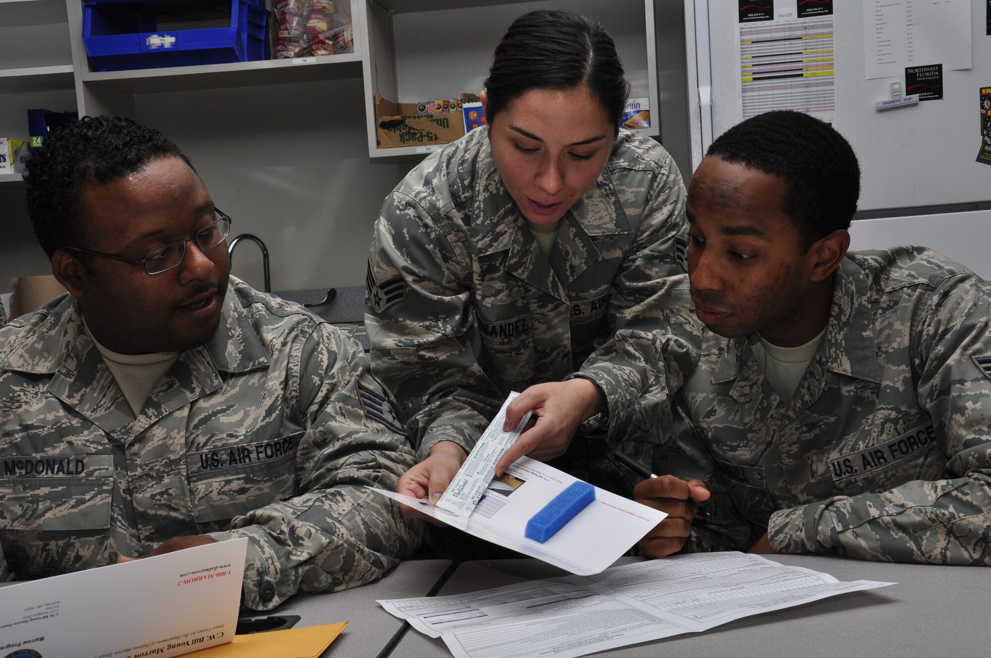Senior Airman Eguzki Fernandez (center) instructs Staff Sgt. Anthony McDonald  and Senior Airman Kenneth McNeill, on how to fill out registration forms during a week-long bone marrow drive, Hurlburt Field, Fla., March 30, 2011. All are from the 1st Special Operations Communications Squadron Tactical Communications Flight. The base-wide drive, initiated by the 1st SOCS, helps support their colleague, Senior Master Sgt. Andy Turnbull, Tactical Communications Flight superintendent, who was diagnosed with acute myeloid leukemia July 19, 2010. (U.S. Air Force photo by Staff Sgt. William Banton/RELEASED) 
