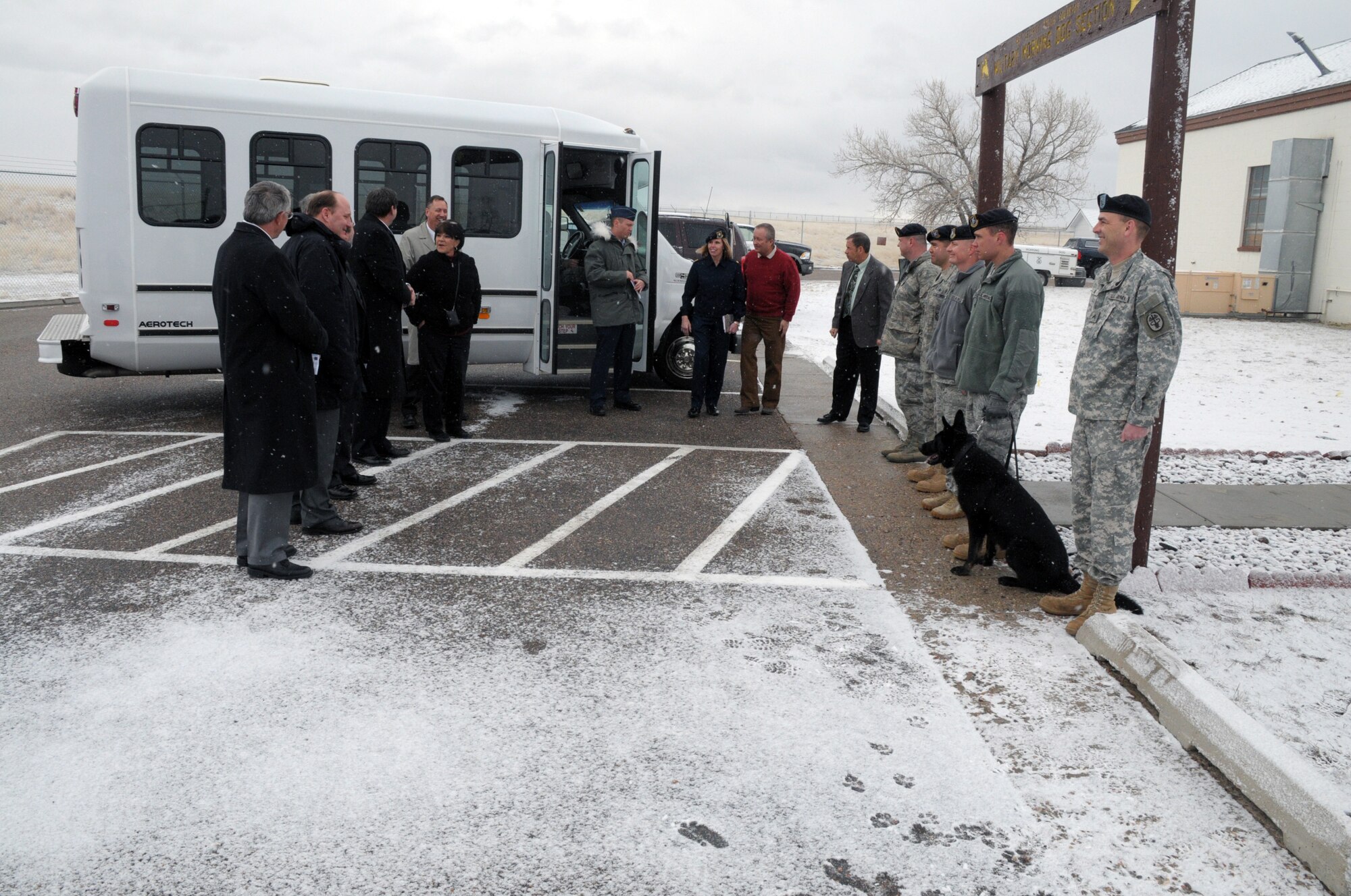 Members of Cheyenne’s Military Affairs Committee, Dale Steenbergen; Jim Wood; Bruce Brady; Scott Meier; Kevin Paintner; Linda Weppner; Ron Van Voast and Max Carre are greeted by Maj. Jutta Arkan and Senior Master Sgt. Joseph Higginbottom, both 90th Security Forces Squadron; Tech. Sgt. James Ramondetta, 90th SFS Kennel Master; Staff Sgt. Derek Copeland and Staff Sgt. Bryan Sodders, 90th SFS; and Kormi, 90th SFS Military Working Dog, outside the MWD facility during the MAC tour of Warren’s facilities March 28. (U.S. Air Force photo by Blaze Lipowski)
