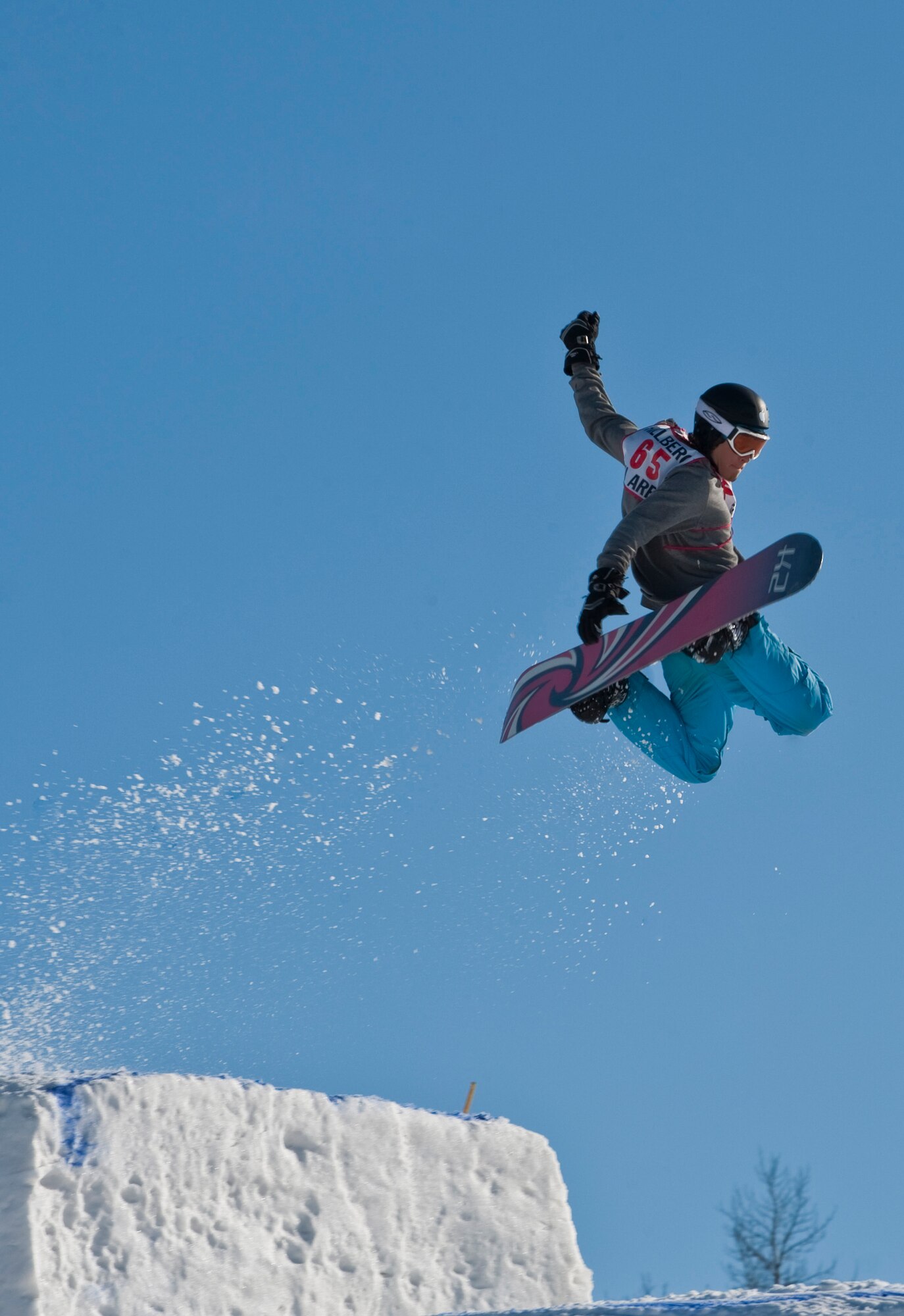 JOINT BASE ELMENDORF-RICHARDSON, Alaska -- Alex Flores goes to grab his board while performing a trick during Hillberg's Annual Melt Down Big Air Competition March 26. During the last few days of the season, various competitions such as the big air competition and annual "Slush Cup" were held. (U.S. Air Force photo by Senior Airman Christopher Gross)