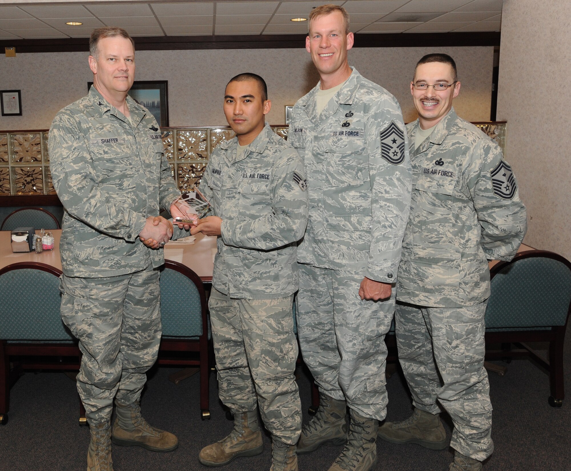 Col. Don Shaffer, 319th Air Base Wing commander, presents Senior Airman Michael Galapate, 319th Communications Squadron, with a Diamond Sharp Award Mar. 31 at Airey Dining Facility here, accompanied by Command Chief Master Sgt. David Carlson, 319th Air Base Wing, and Senior Master Sgt. Keith Waltz, 319th Medical Group/Communications Squadron first sergeant. The Diamond Sharp Award is given to those Airmen who epitomize service before self and strive for excellence at work and off duty. (U.S. Air Force photo by Staff Sgt. Suellyn Nuckolls)