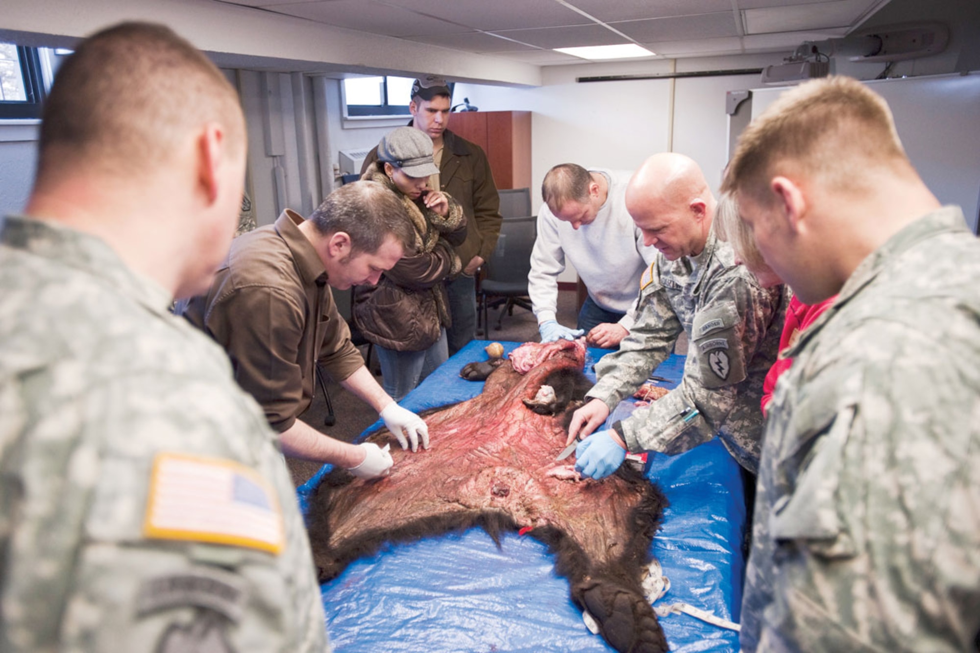 Air Force Master Sgt. Kevin McDonald, white sweatshirt, shows members of the Warrior
Transition Unit how to properly skin a bear March 25. (U.S. Air Force photo/Senior Airman Christopher Gross)
