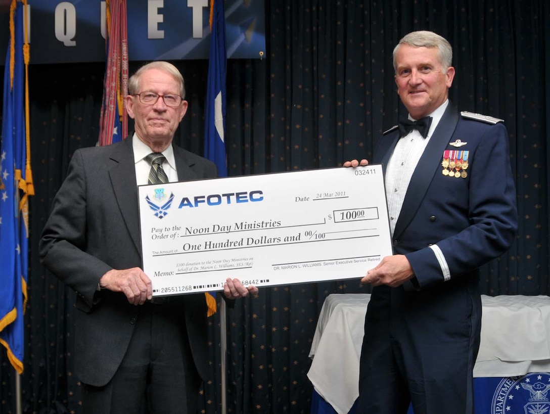 Air Force Operational Test and Evaluation Center Commander Maj. Gen. David J. Eichhorn (right) presents Dr. Marion L. Williams a donation to Noon Day Ministries in his name in appreciation for being a guest speaker at the March 24, 2010 AFOTEC Annual Awards Banquet.