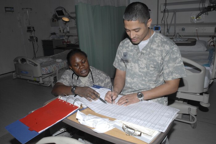 BAGRAM AIR FIELD, Afghanistan — Capt. Bomidele Adetunji, Craig Joint Theater Hospital critical care nurse, and Staff Sgt. Andrade Borbor, CJTH critical care technician, review a patient's chart in the intensive care unit of the hospital, March 17, at Bagram Air Field, Afghanistan. Captain Adetunji is deployed from Nellis Air Force Base, Nev., and Sergeant Borbor is deployed from Travis Air Force Base, Calif. (Air Force photograph by Senior Airman Amber R. Kelly-Herard)